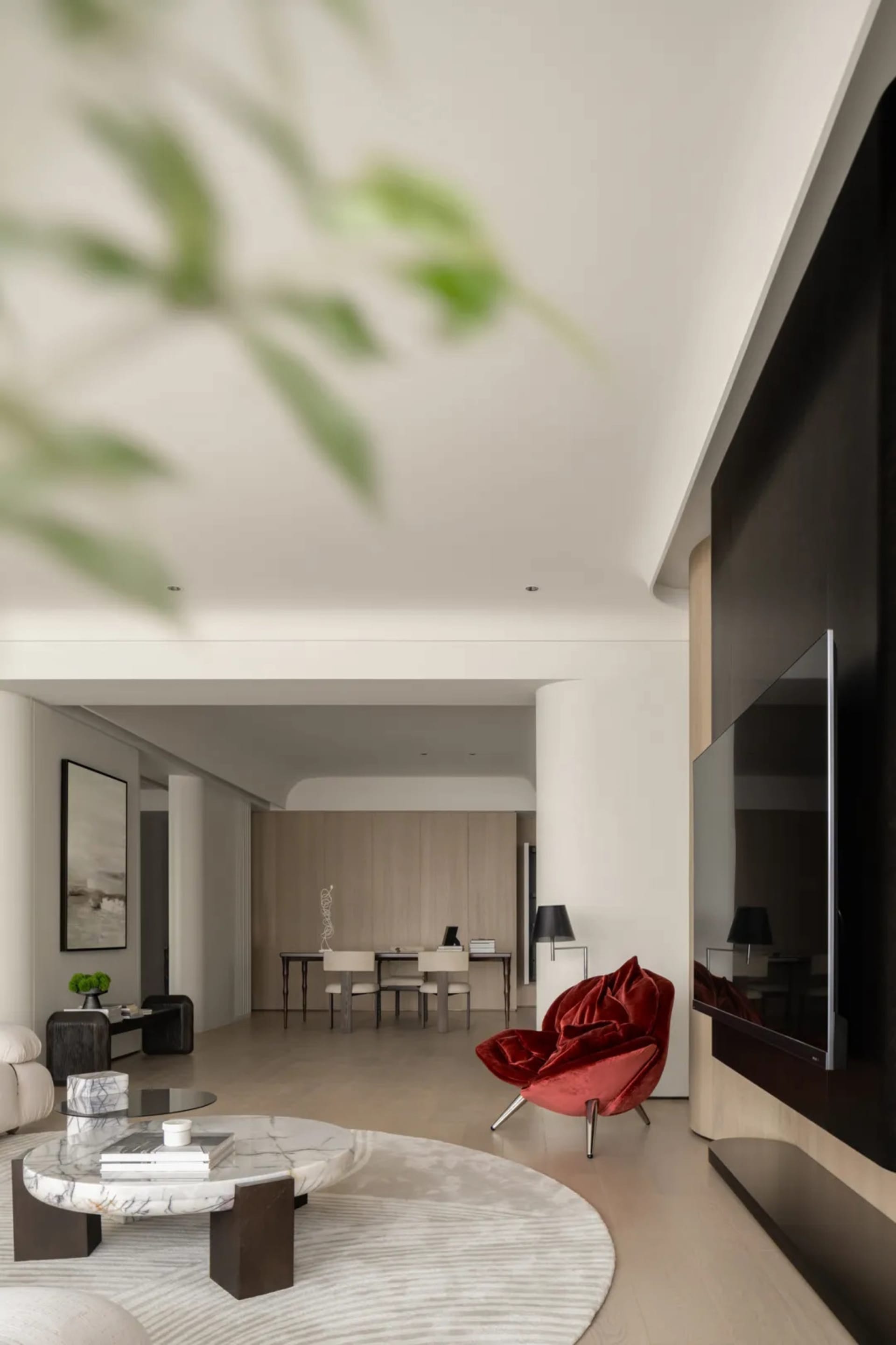 Minimalist living room with marble coffee table, red armchair, and flat-screen TV.