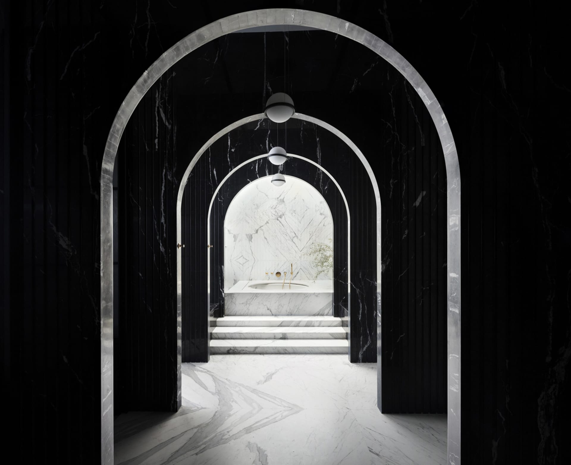 A modern minimalist bathroom with black marble walls and a white marble bathtub surrounded by recessed archways.