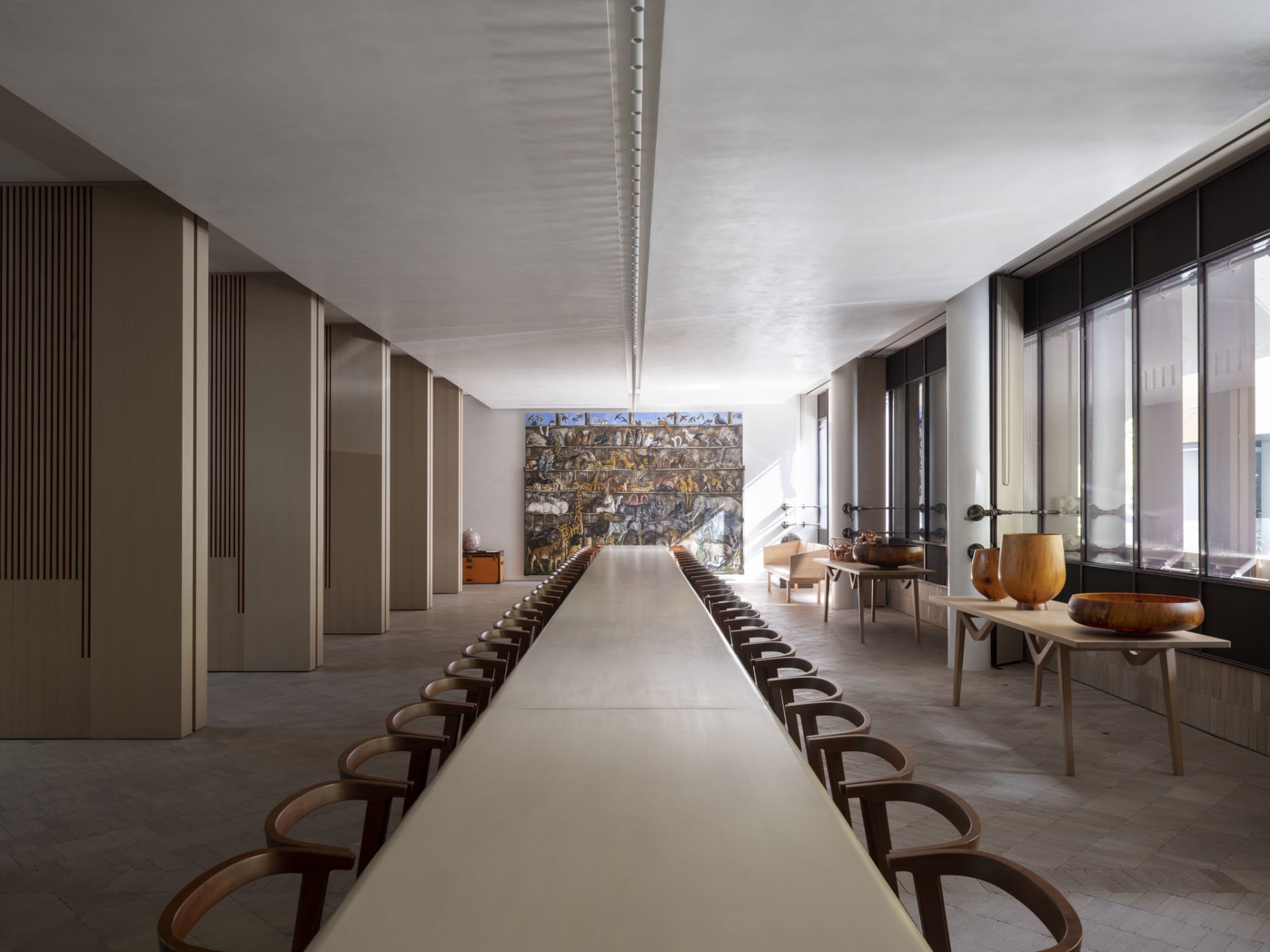 Modern restaurant interior featuring long wooden tables, ceramic sculptures, and a large mural depicting various animals.