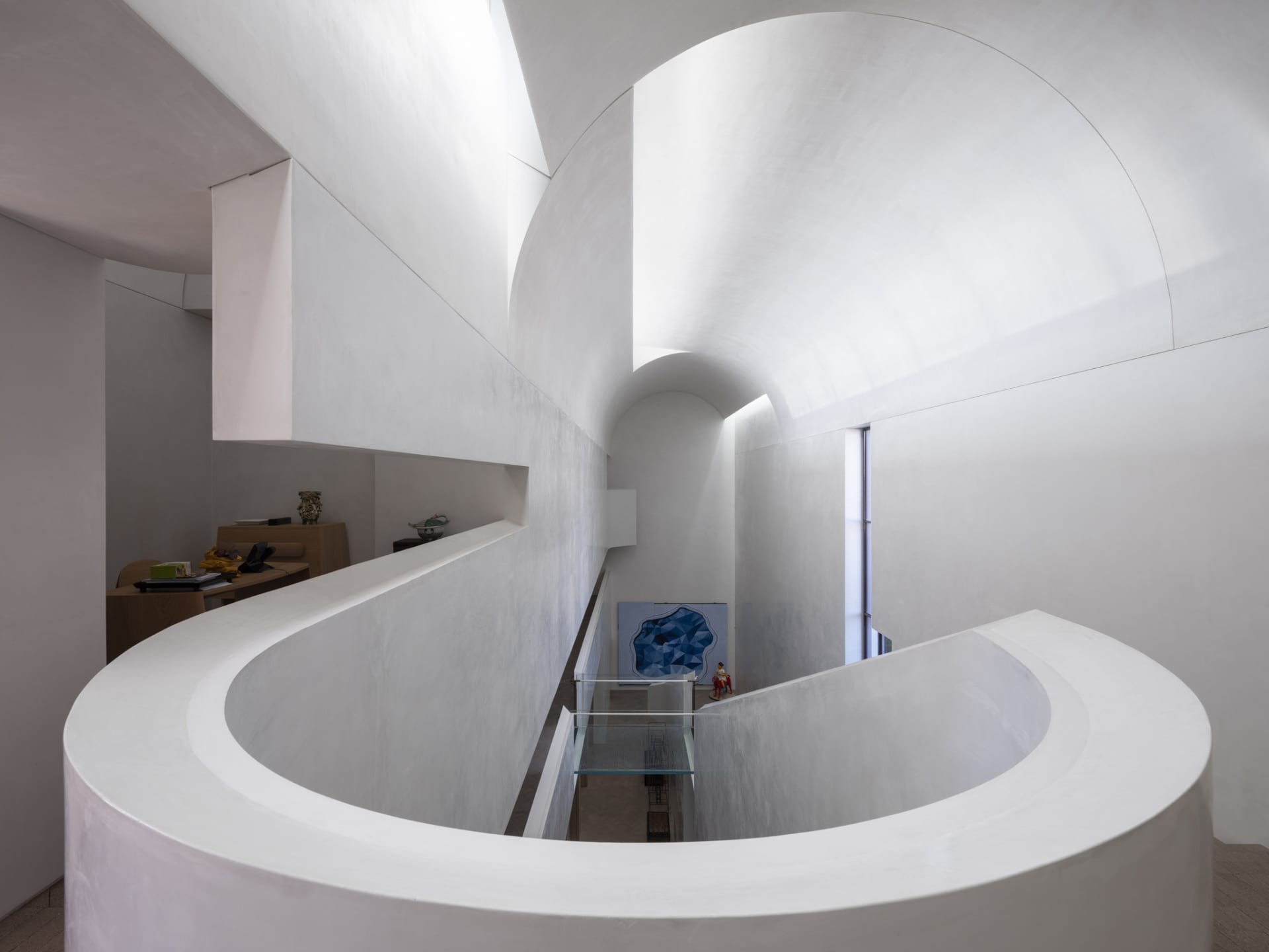Modern white interior featuring a curved concrete staircase.