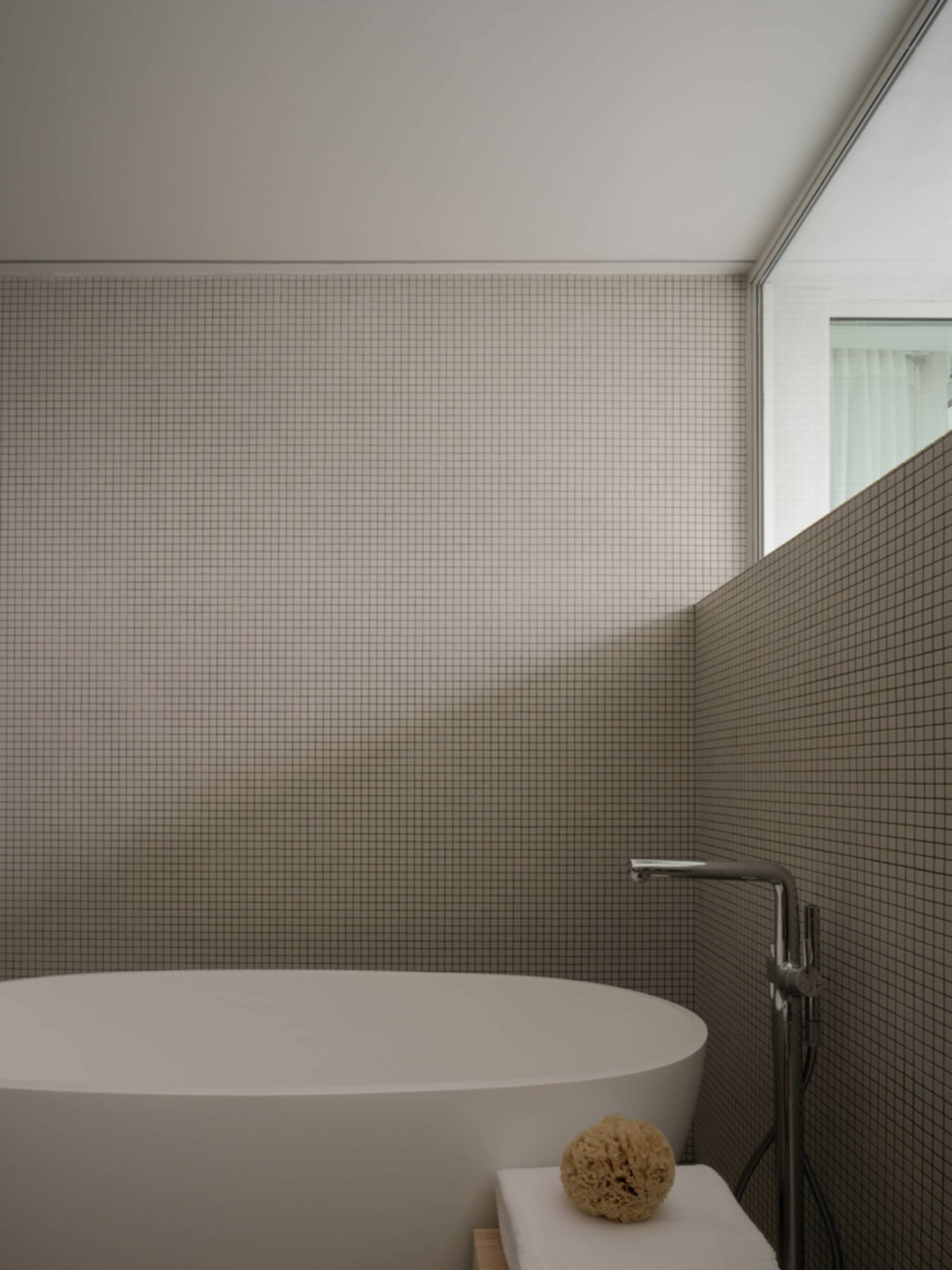 A minimalist bathroom with tiled walls and a freestanding bathtub.