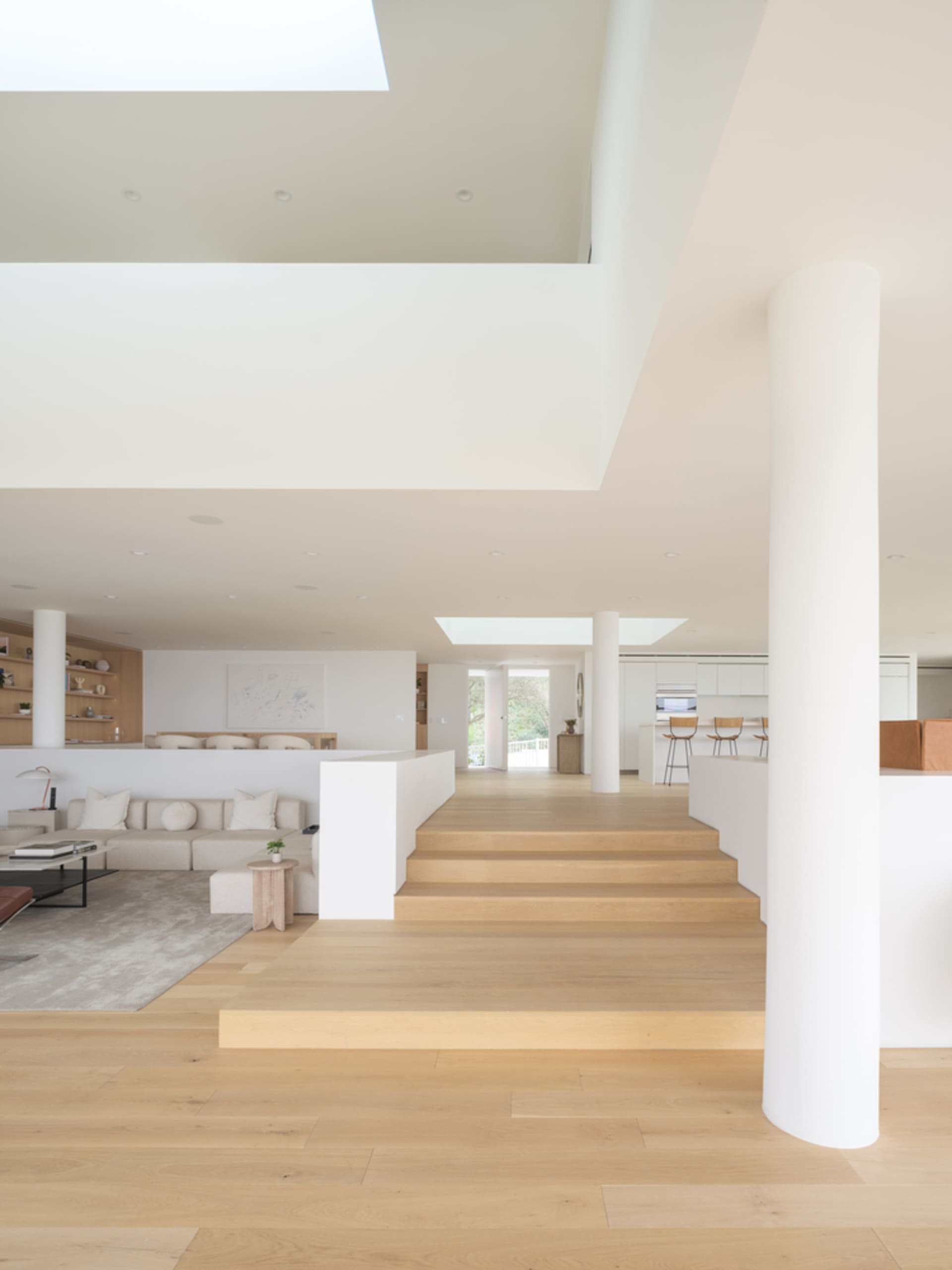 Light wood floor and minimalist living room with white furniture and a sky window
