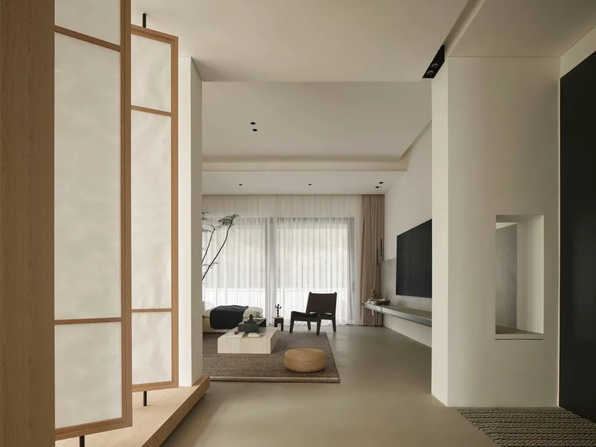 A minimalist living room featuring concrete furniture, wooden accents, and fabric textiles.