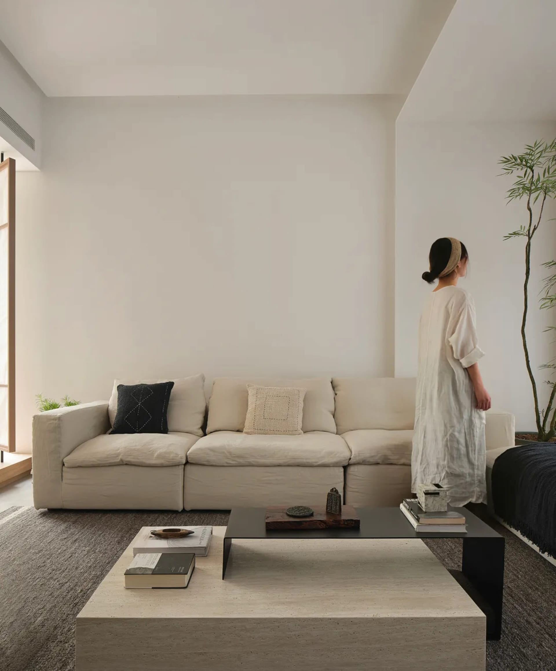 A minimalist living room featuring a beige sofa with natural fiber throw pillows and a contemporary black and beige square co