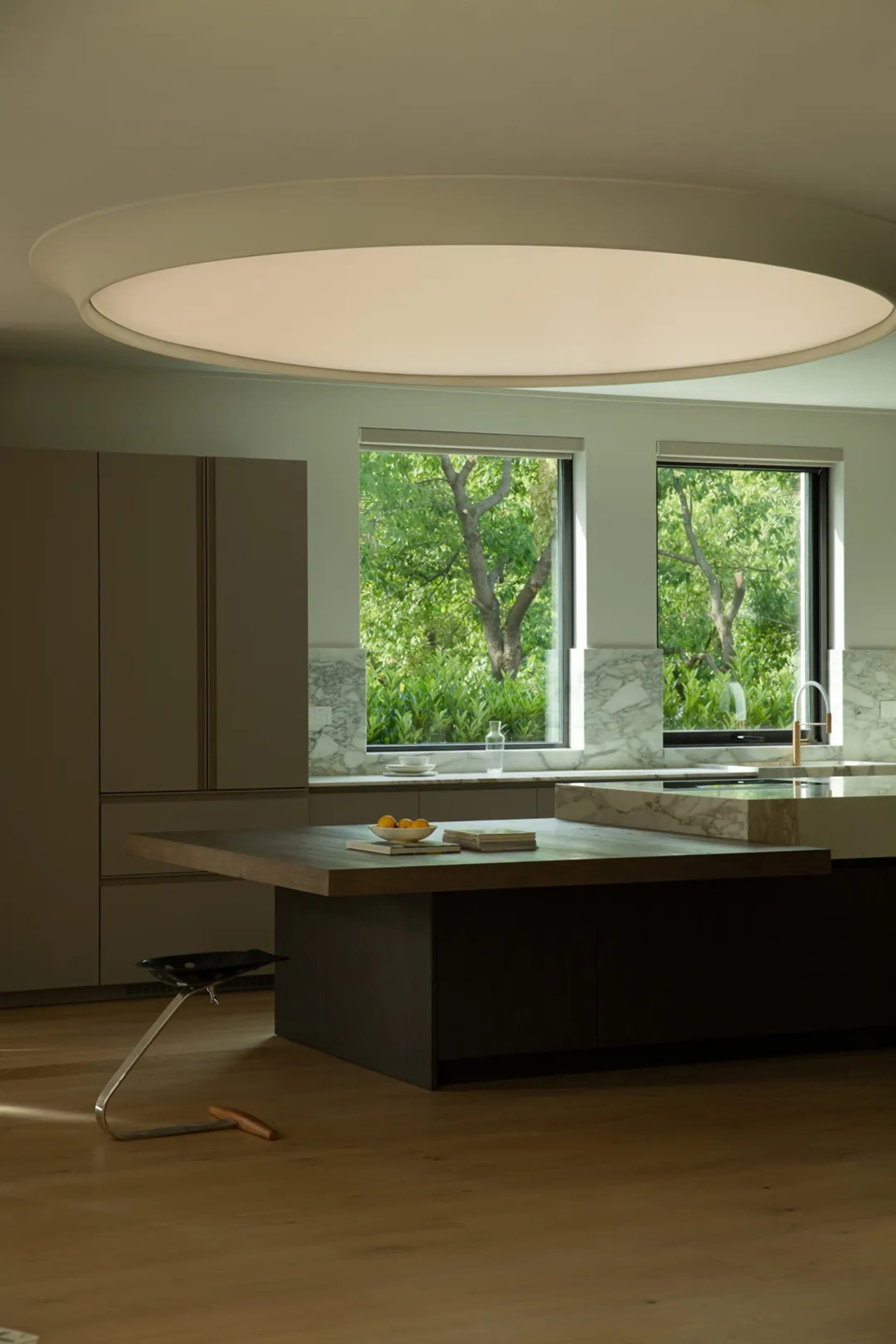 A well-lit residential kitchen features a large island with a wooden countertop and a marble backsplash, surrounded by minima