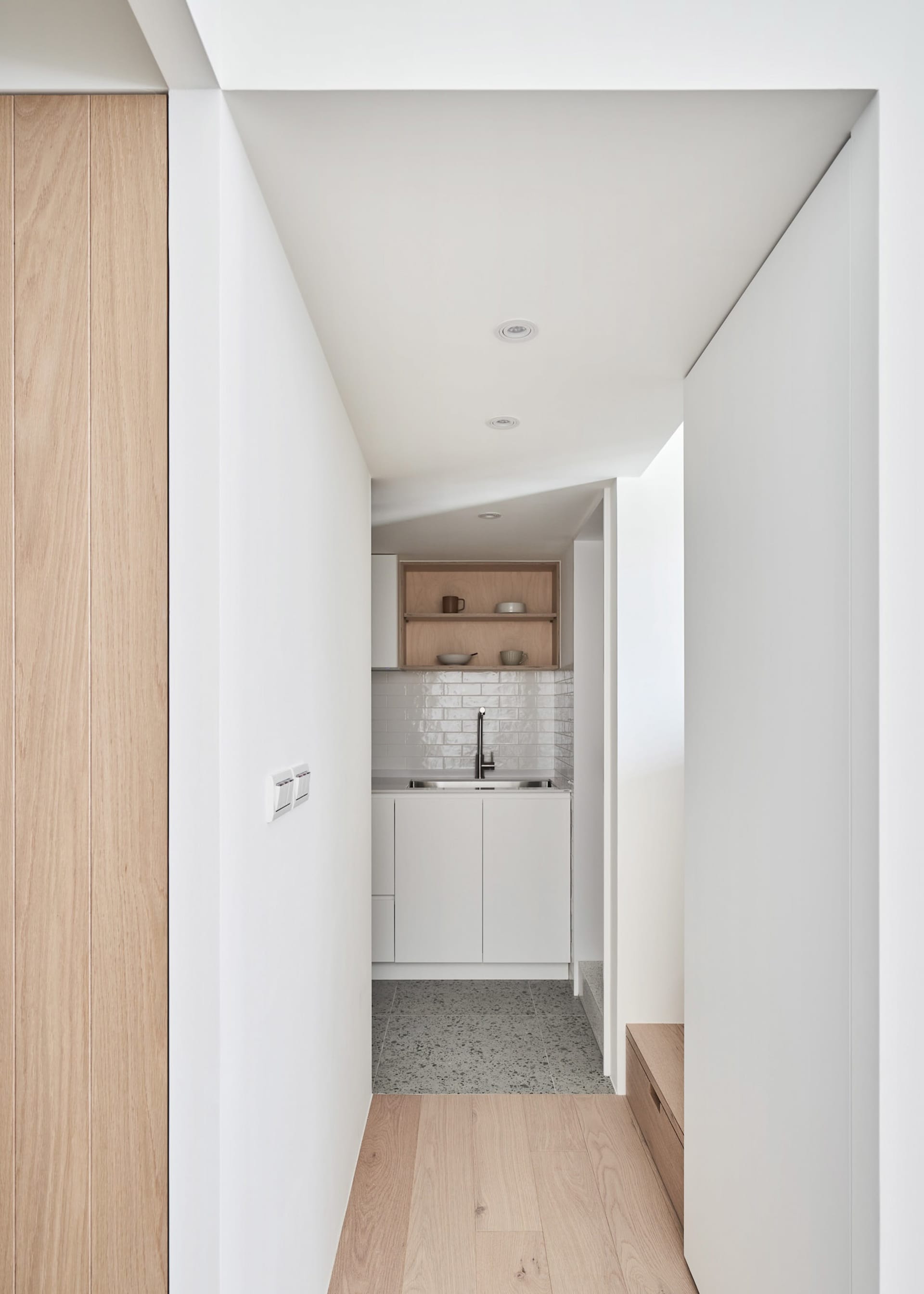 A minimalist kitchen with white countertops and wooden accents