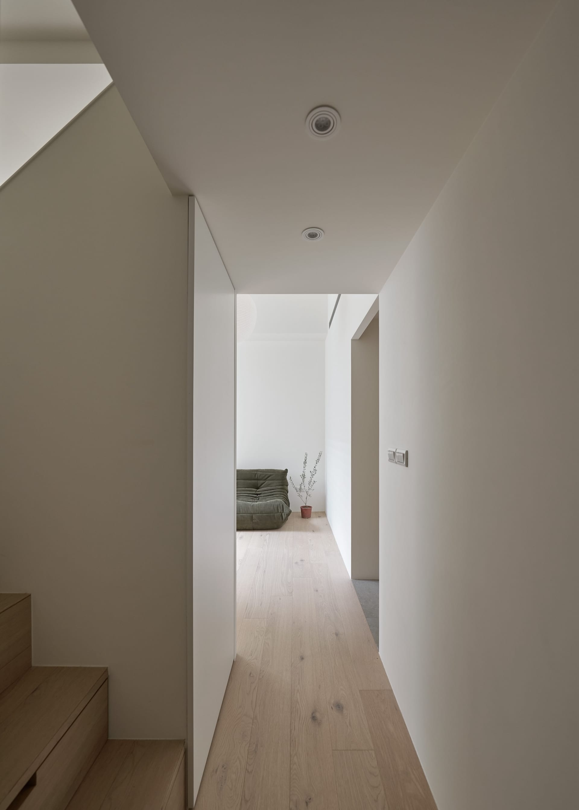 A minimalist living room with wooden flooring and a green sofa.