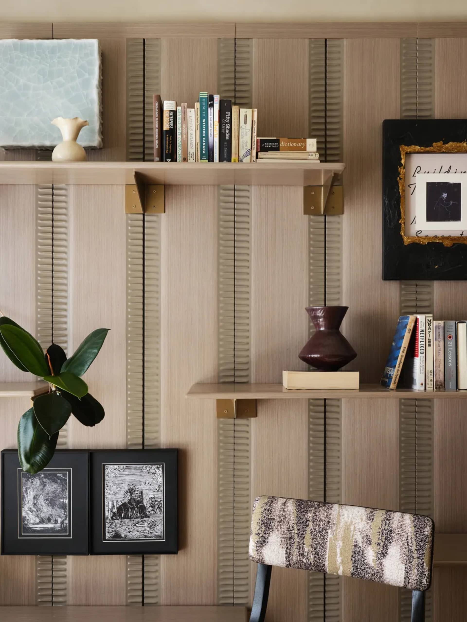 A modern office with a bookshelf, chair, and decorative vases.