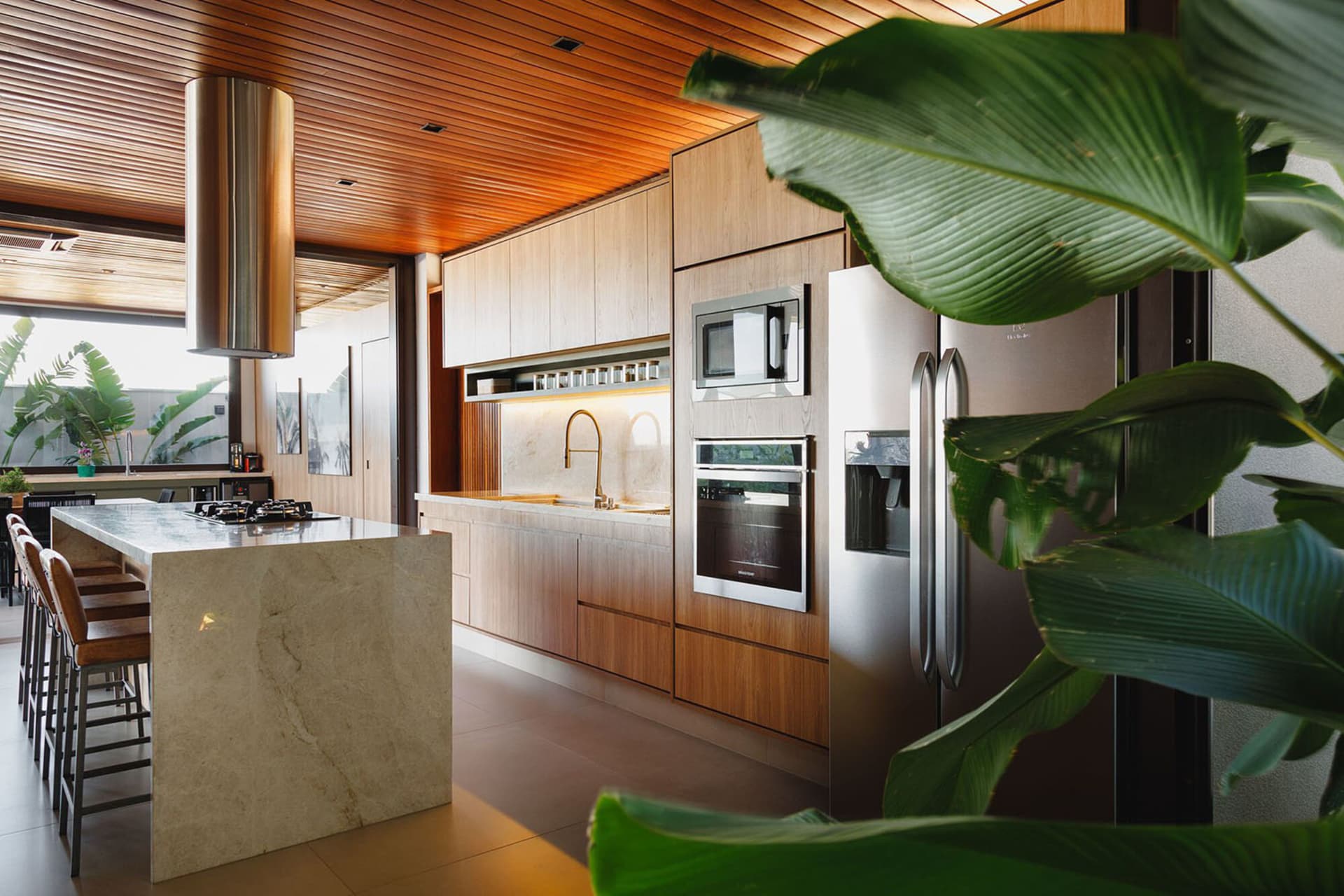 Modern, minimalist kitchen featuring marble countertops and wood cabinetry.