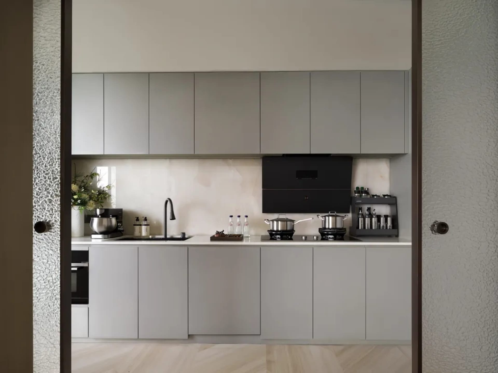 Modern, minimalist kitchen with gray oak cabinets, stainless steel appliances, and a neutral color palette.