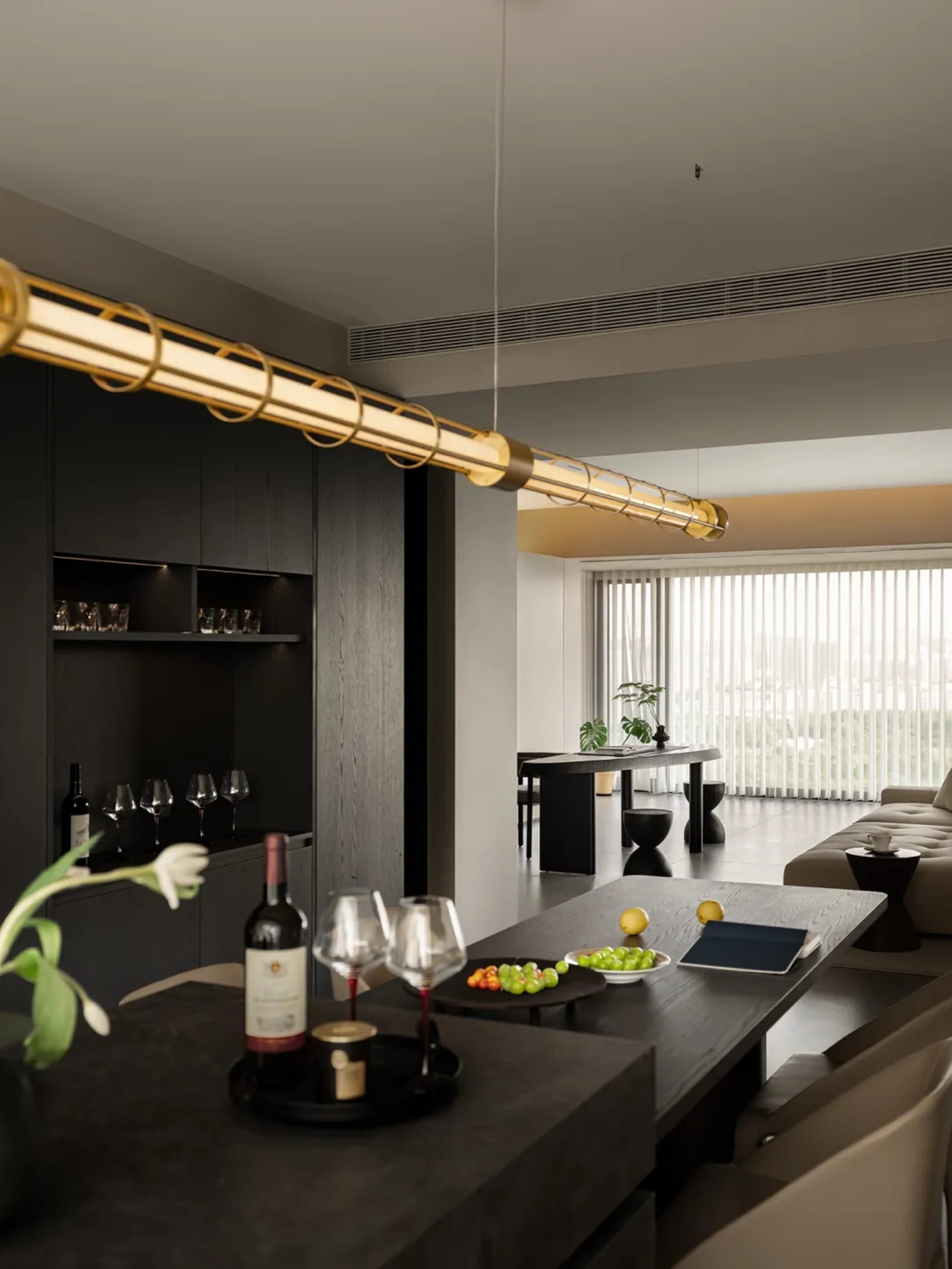 A modern dining room with black wooden furniture and a sleek, minimalist design. Decorated with white flowers, fruit, and win