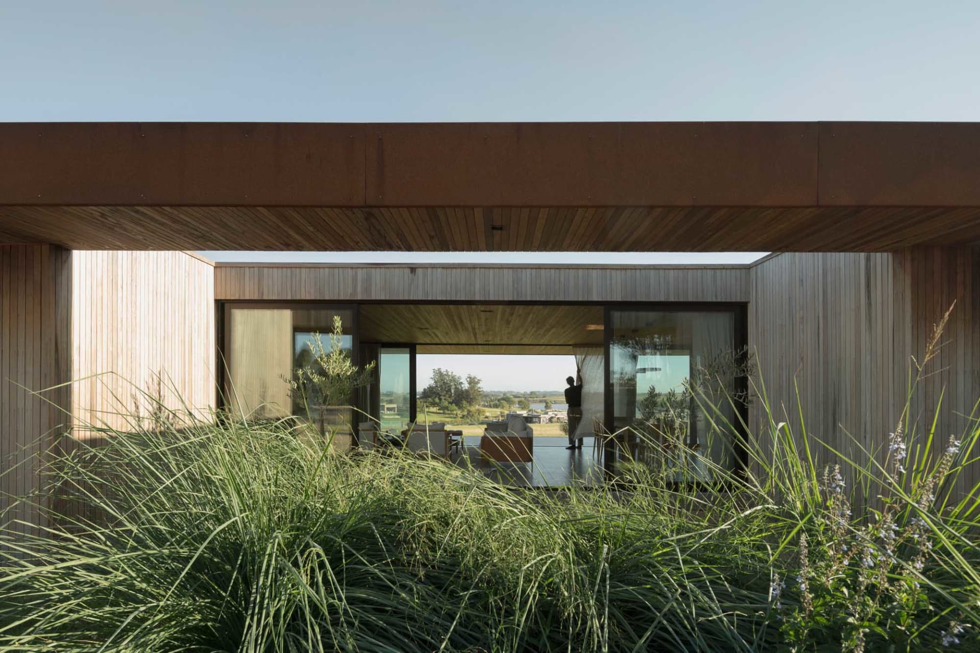 A modern house with large glass windows showing an indoor living space.
