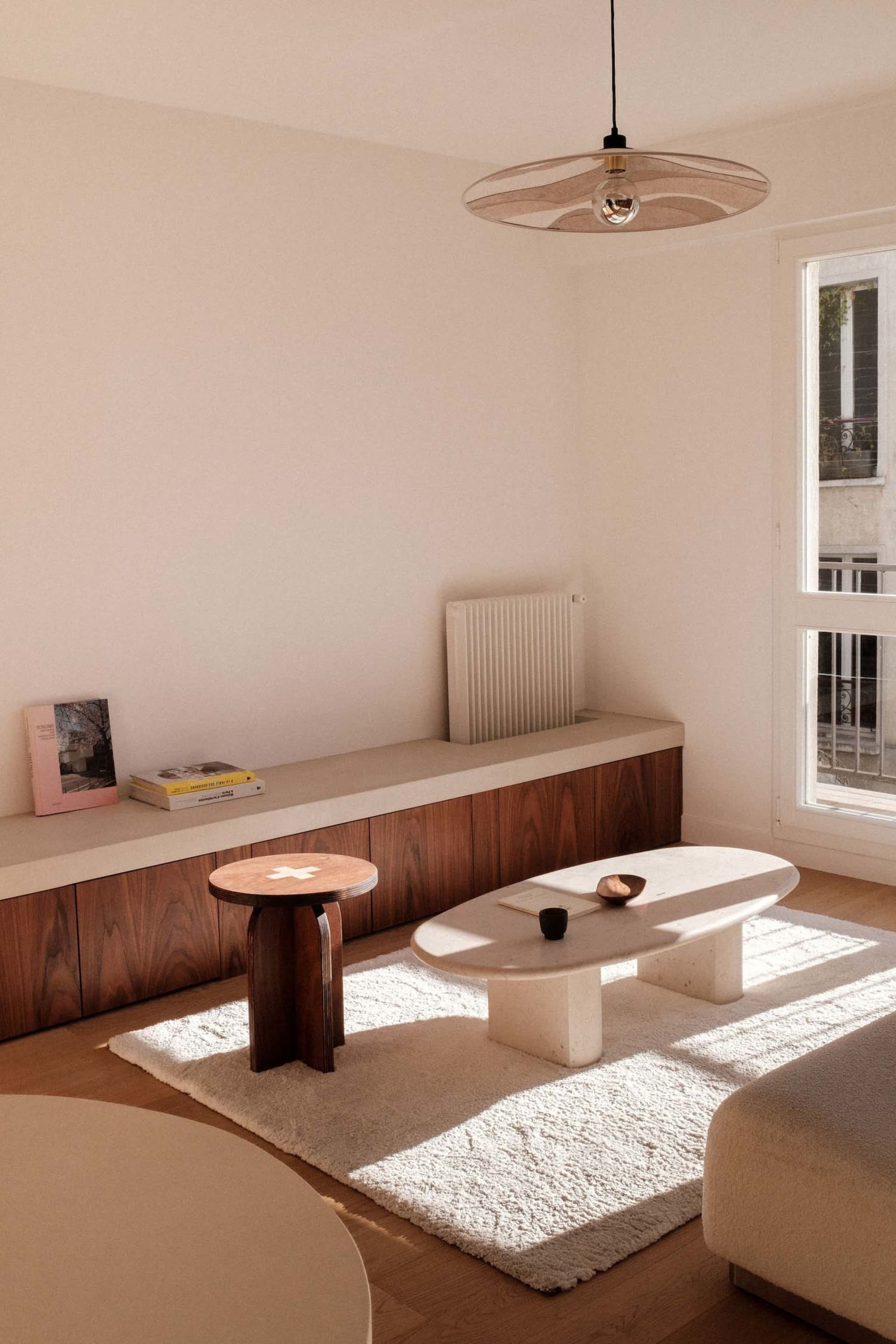 Modern minimalist living room featuring marble and wooden furniture, with a concrete floor and white rug.