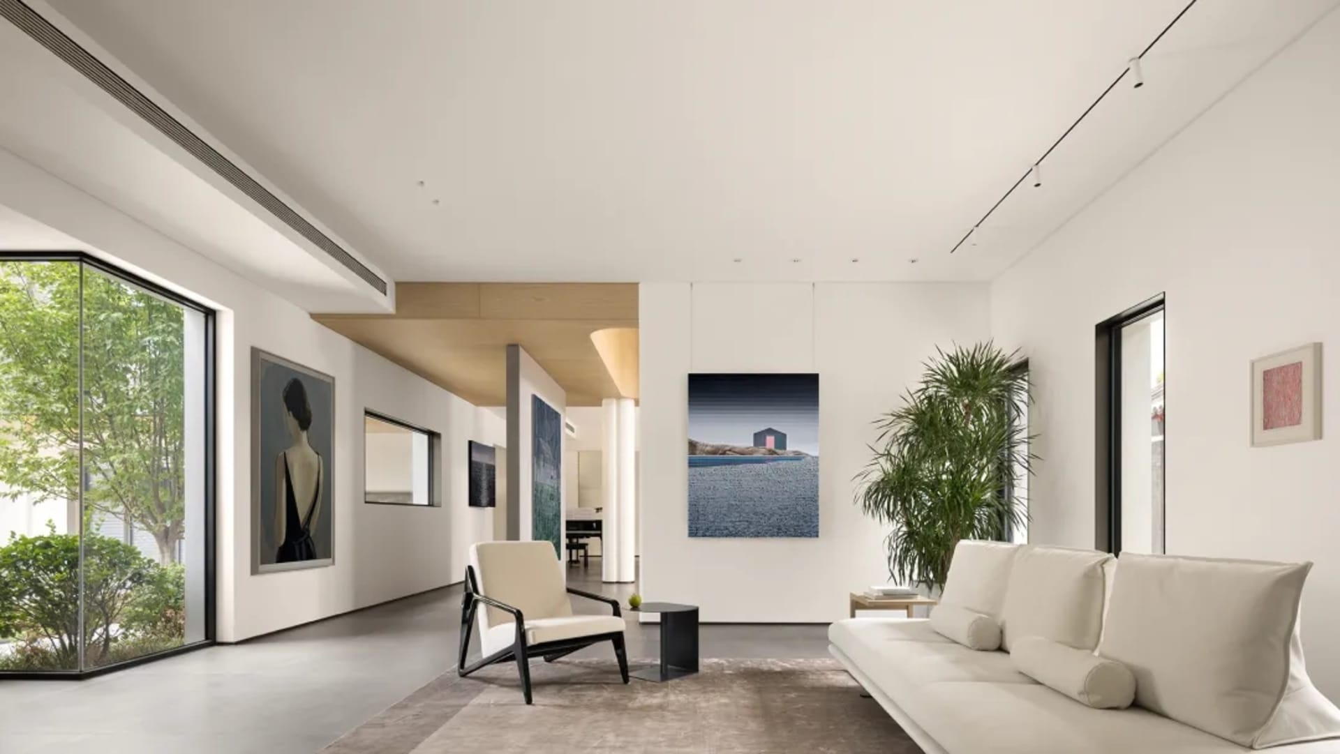Minimalist living room with concrete tiles, white sofa, armchair, and framed artwork.