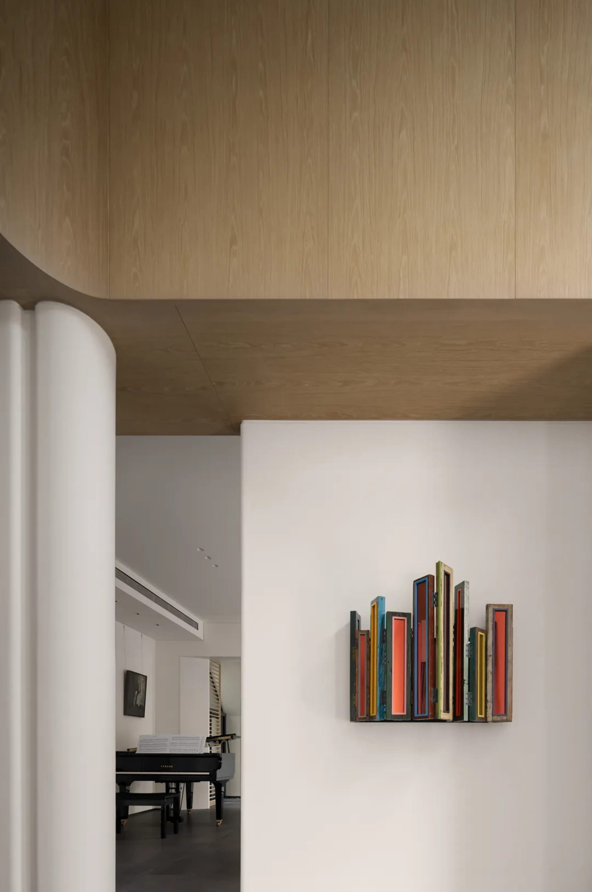 A minimalist living room featuring a wooden bookshelf with colorful books.