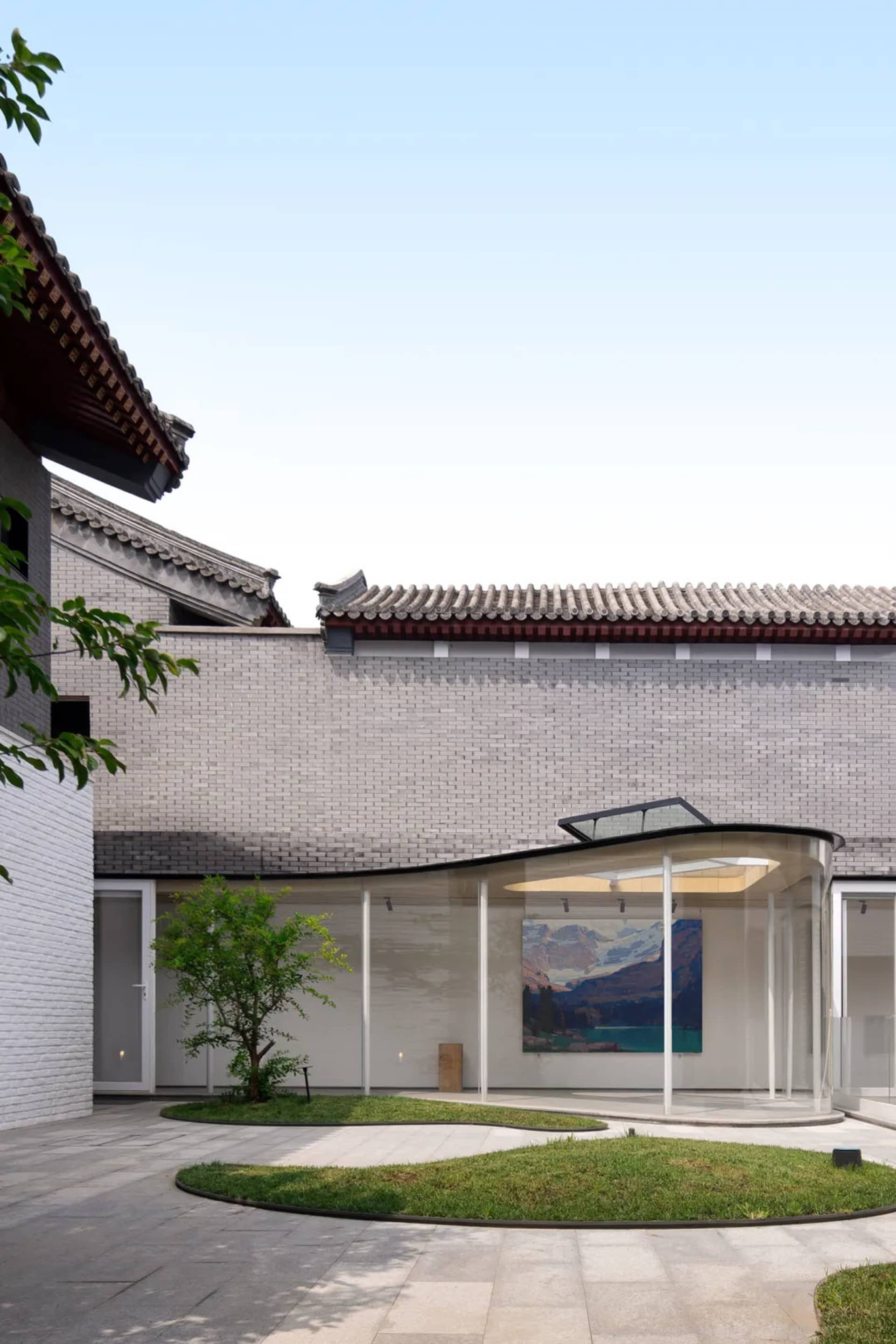 Modern building exterior with white brick walls and gray tiled roof.