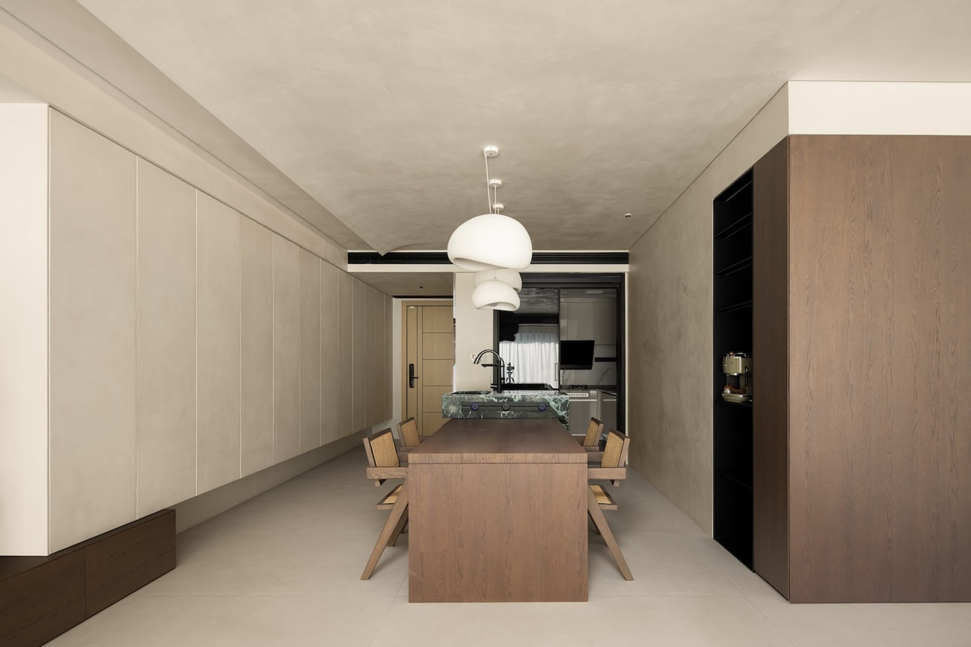Modern kitchen and dining area with wooden table, marble countertop, and white pendant lights.