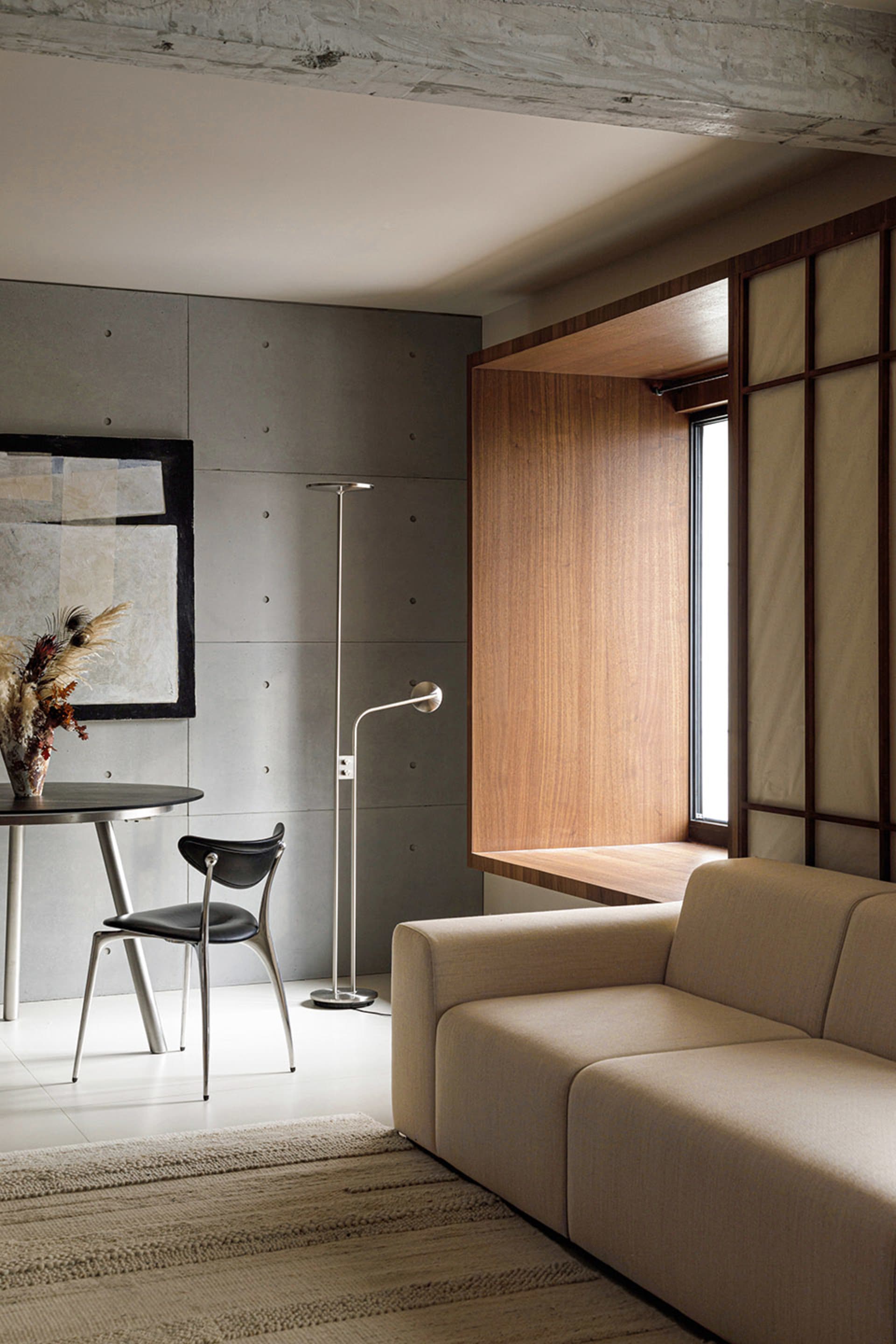 A modern living room featuring a concrete wall and a wooden window bench.
