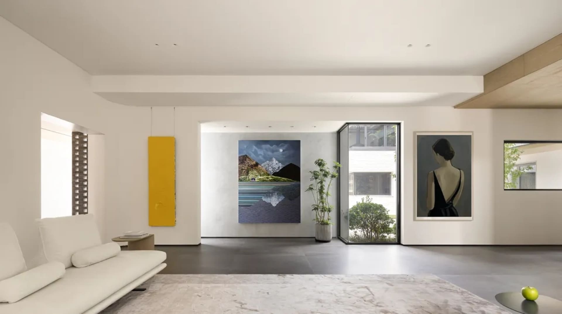 A modern minimalist living room with concrete flooring and wooden accents.