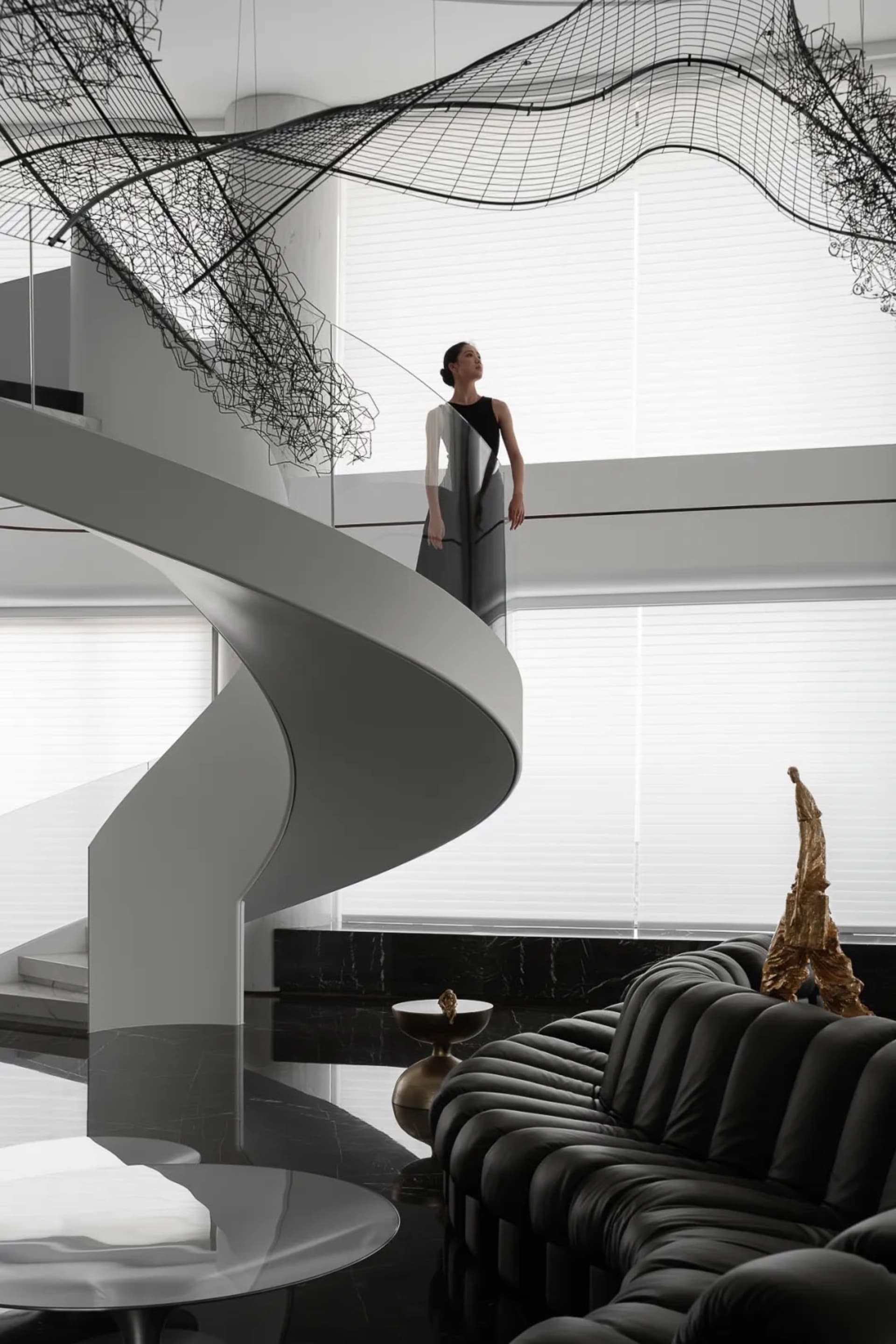 A modern residential living space featuring a sleek black spiral staircase with metal railings, glass panels, and stone accen