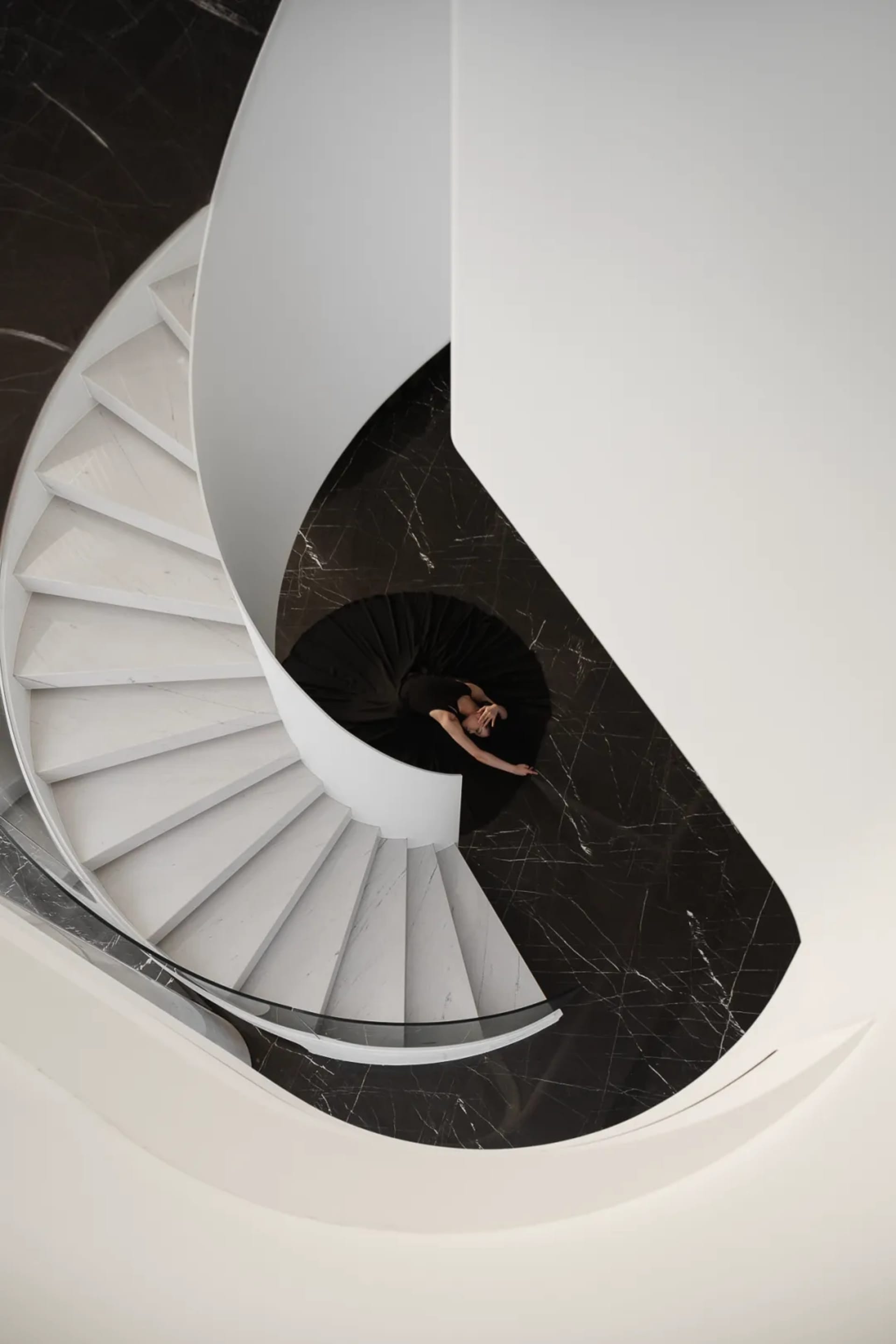 A modern staircase featuring white marble steps and black marble floor.