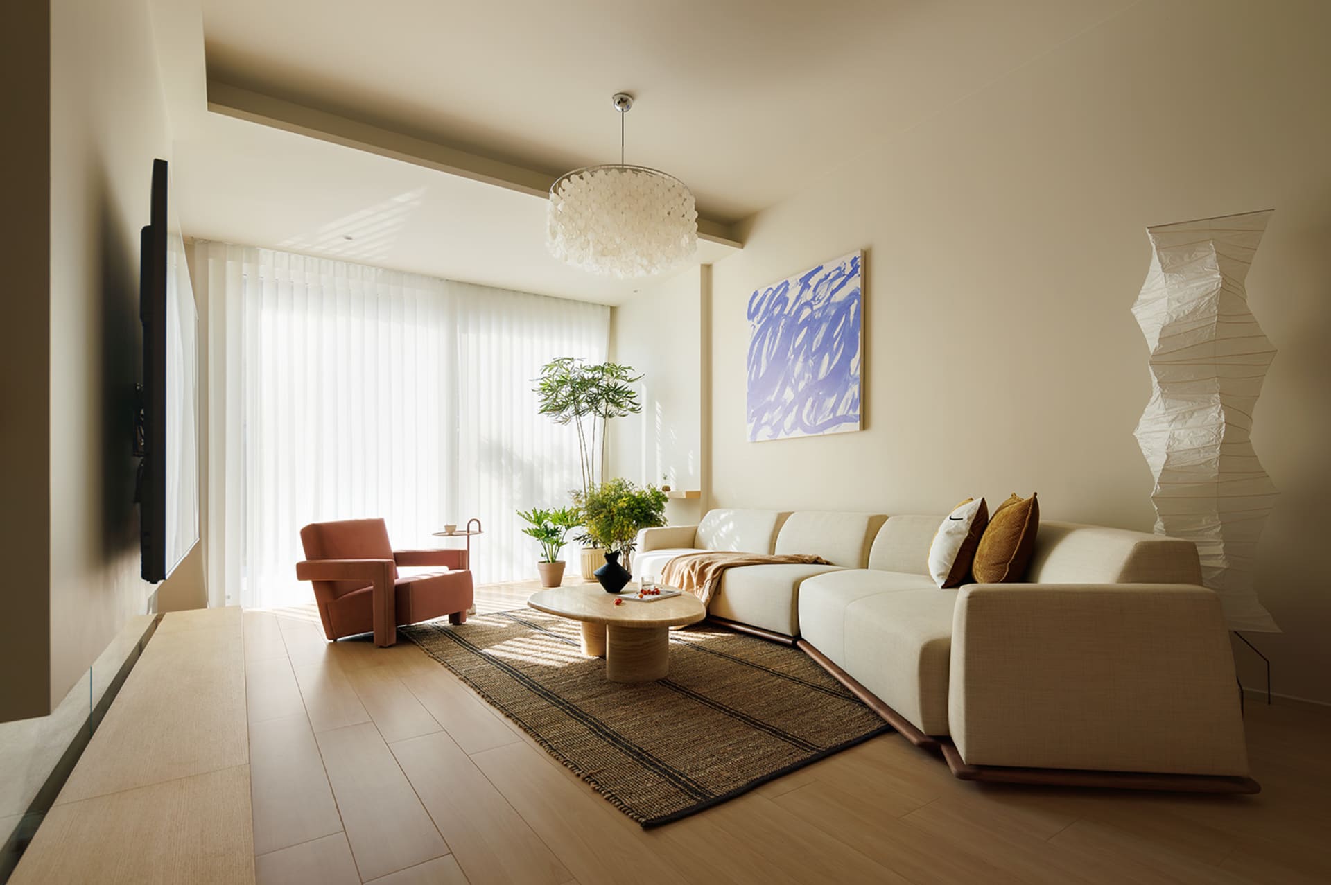 A modern living room featuring neutral-toned furniture and wood flooring.