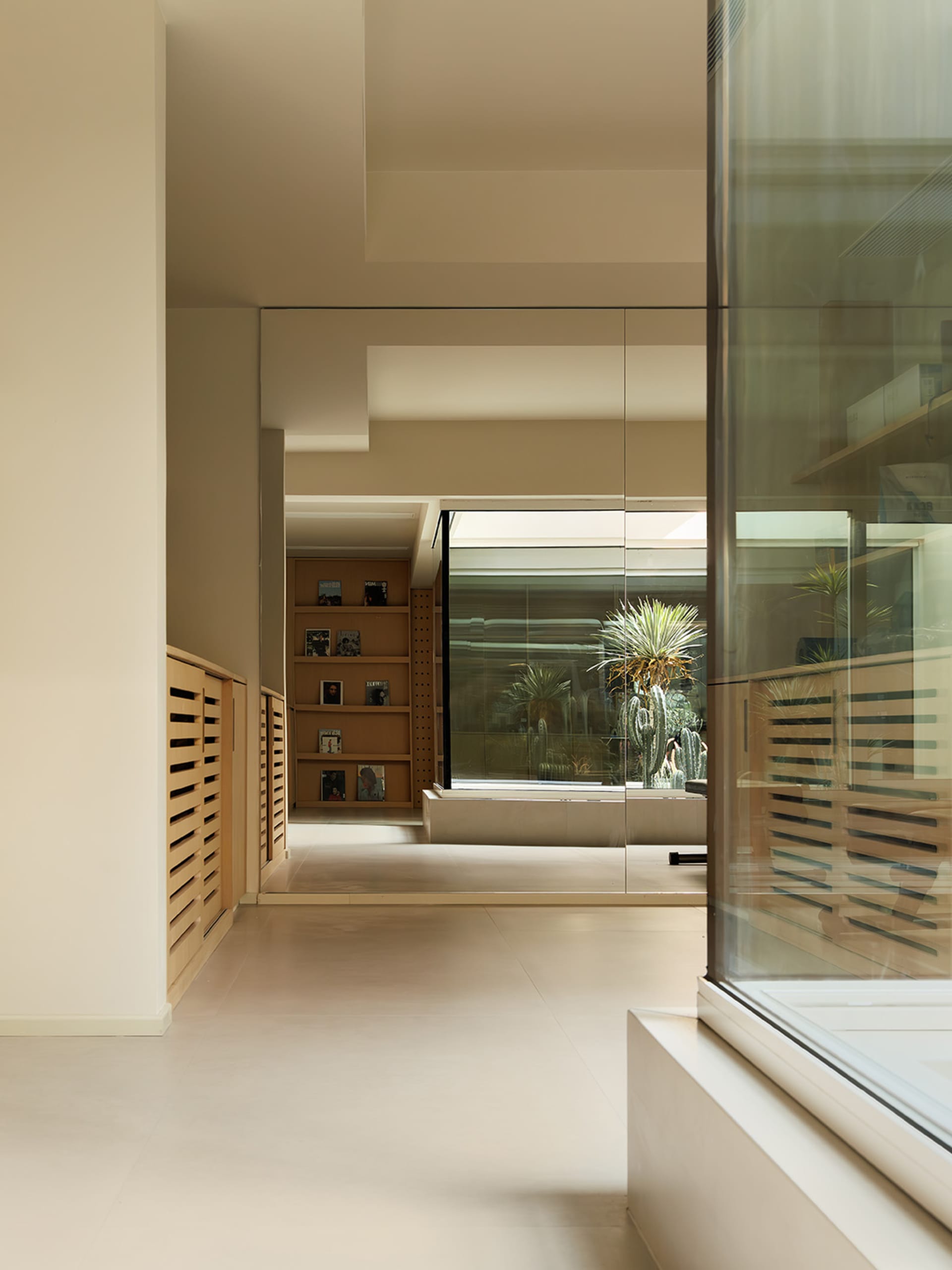 A modern minimalist library with glass walls and wooden shelves.