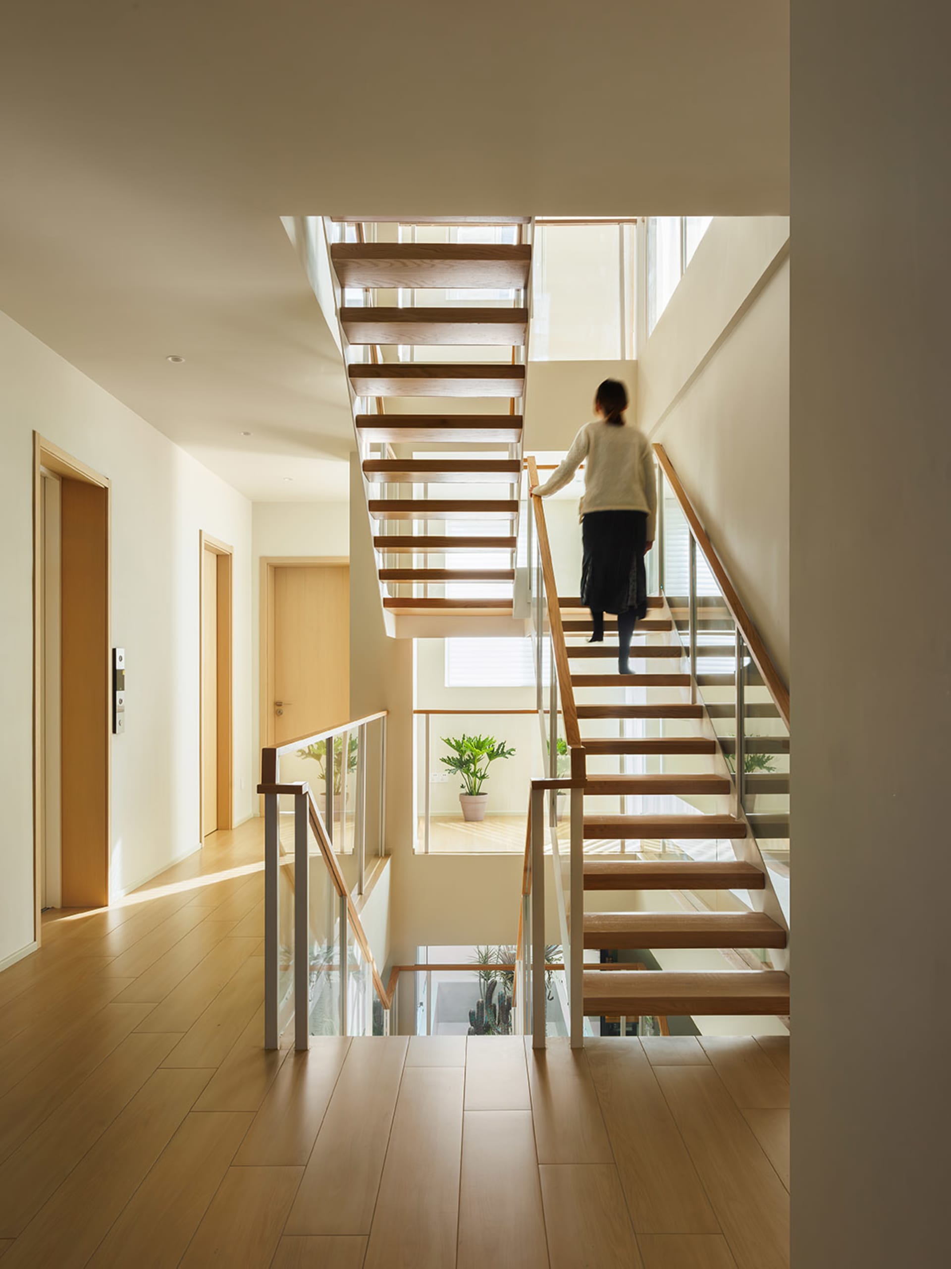 A modern interior featuring wooden stairs with glass railings.