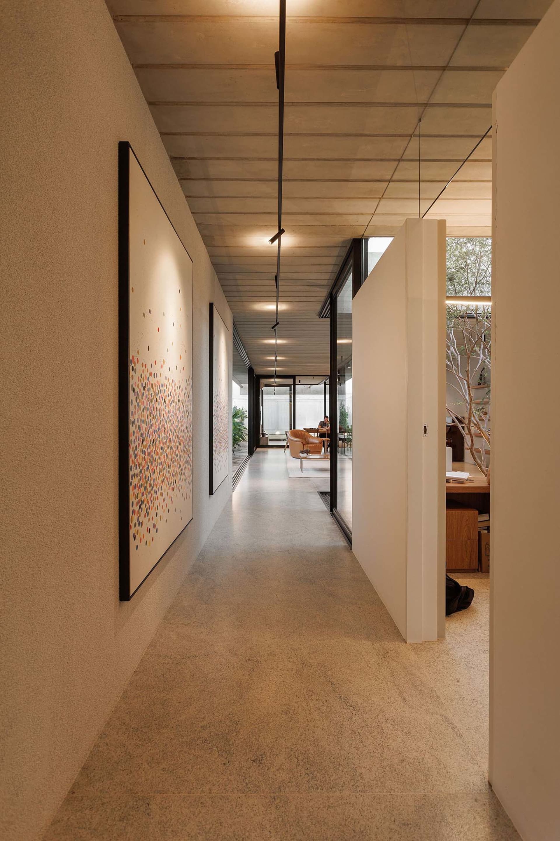 Modern minimalist interior with concrete tiles, white walls, and geometric lighting fixture.