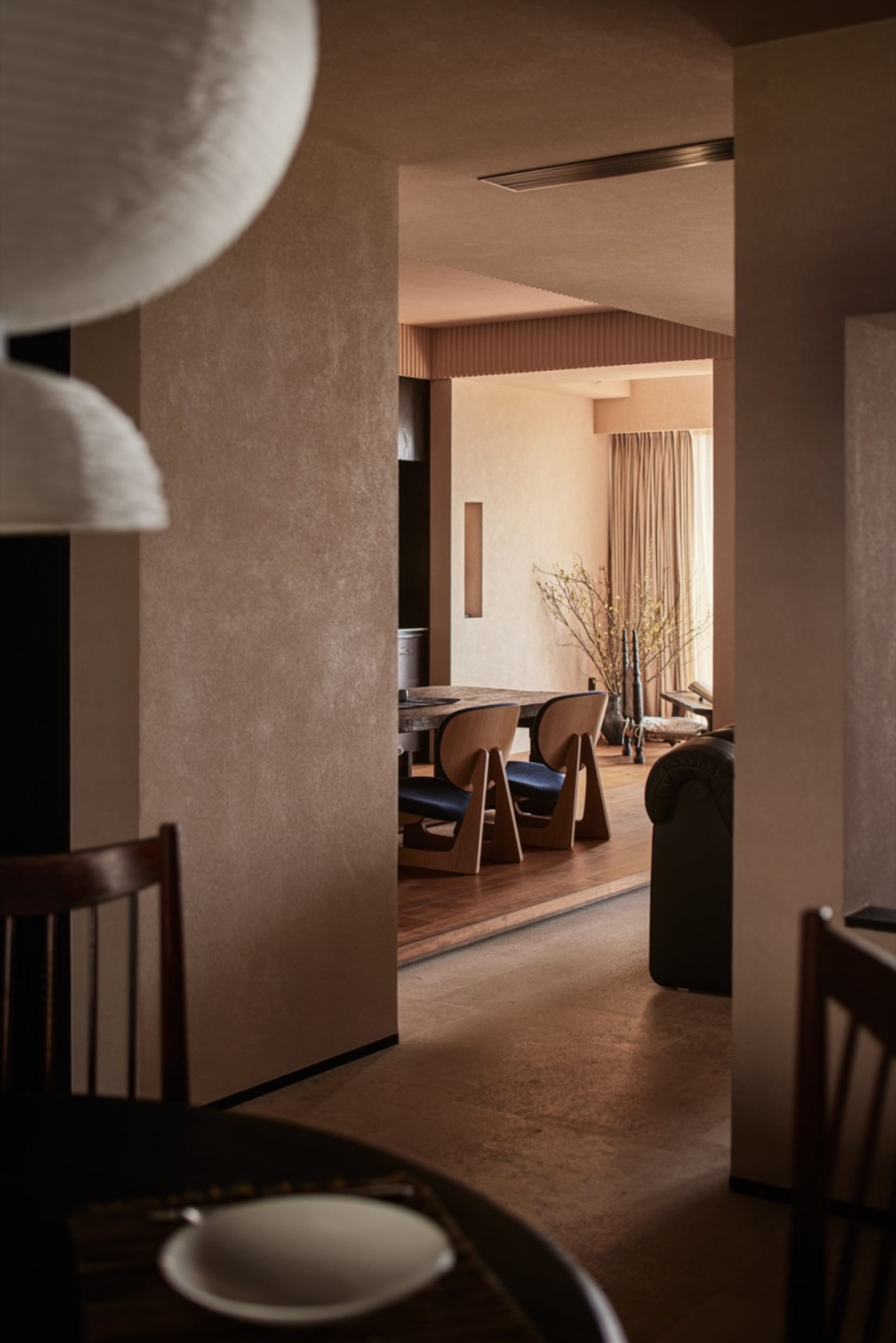 A modern minimalist dining room featuring wooden furniture and light-colored walls.