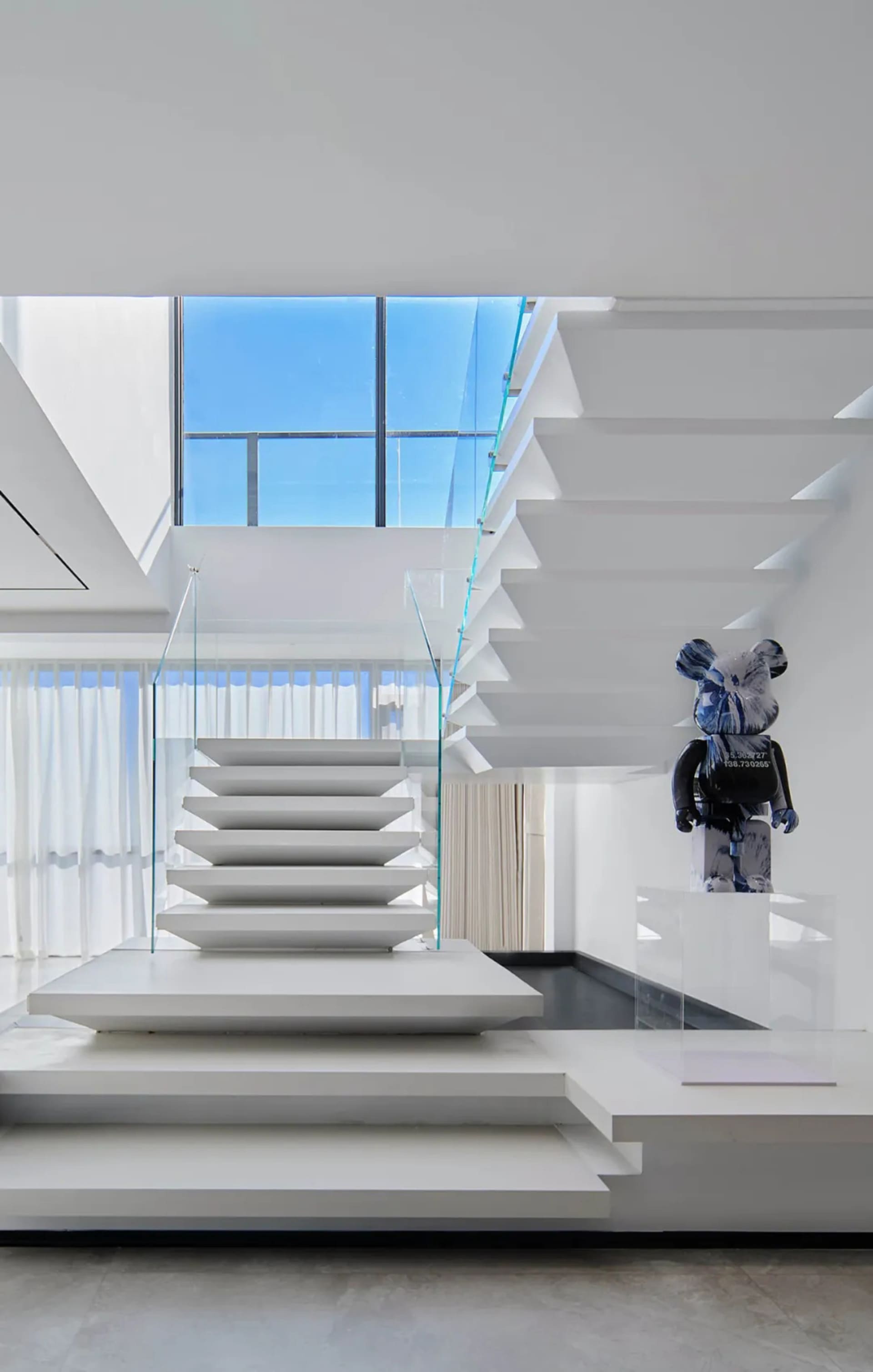 Modern staircase featuring glass railings and concrete steps.