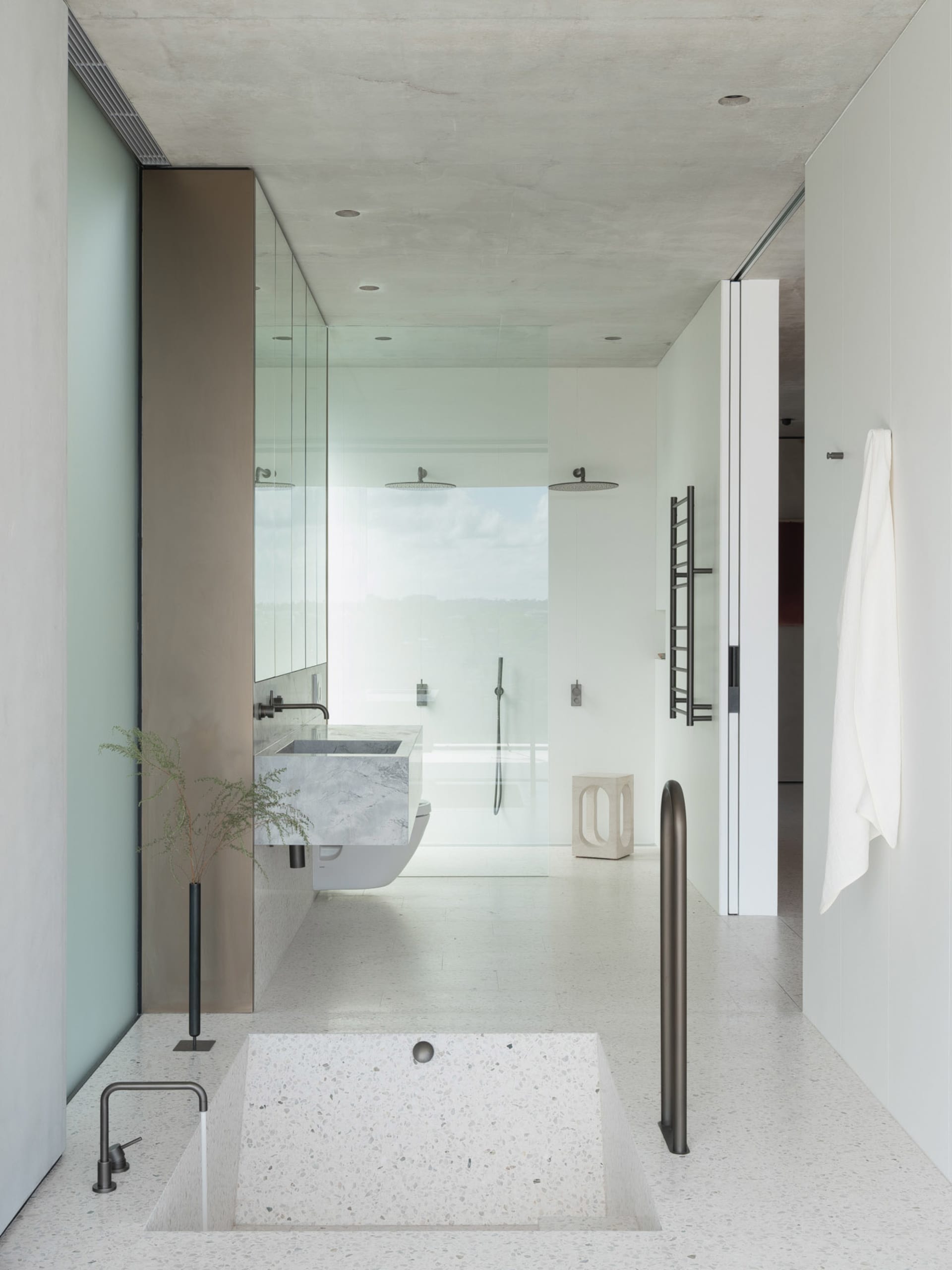 Modern minimalist bathroom featuring concrete, glass, and terrazzo elements.