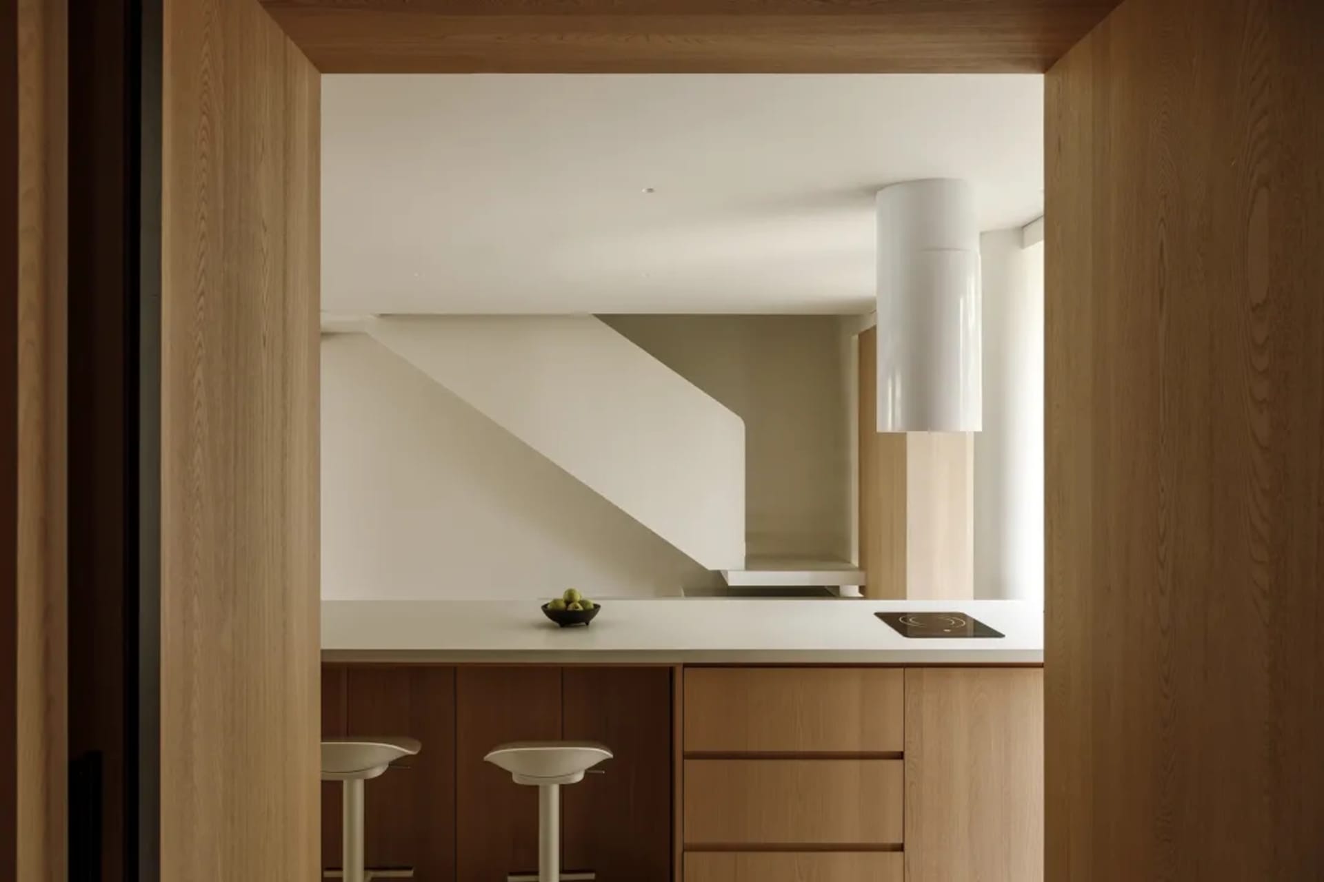 Modern minimalist kitchen with wooden cabinets and a white countertop.