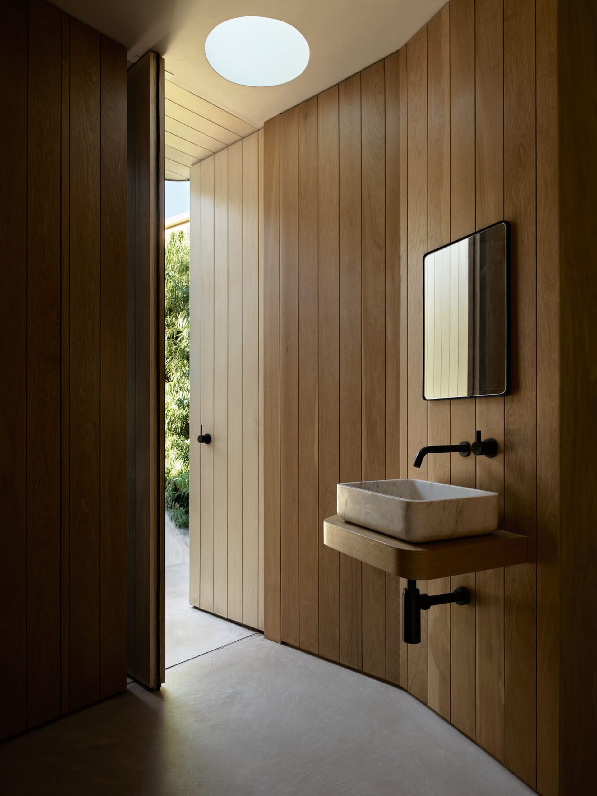 A minimalist bathroom with wooden walls and a floating vanity sink.