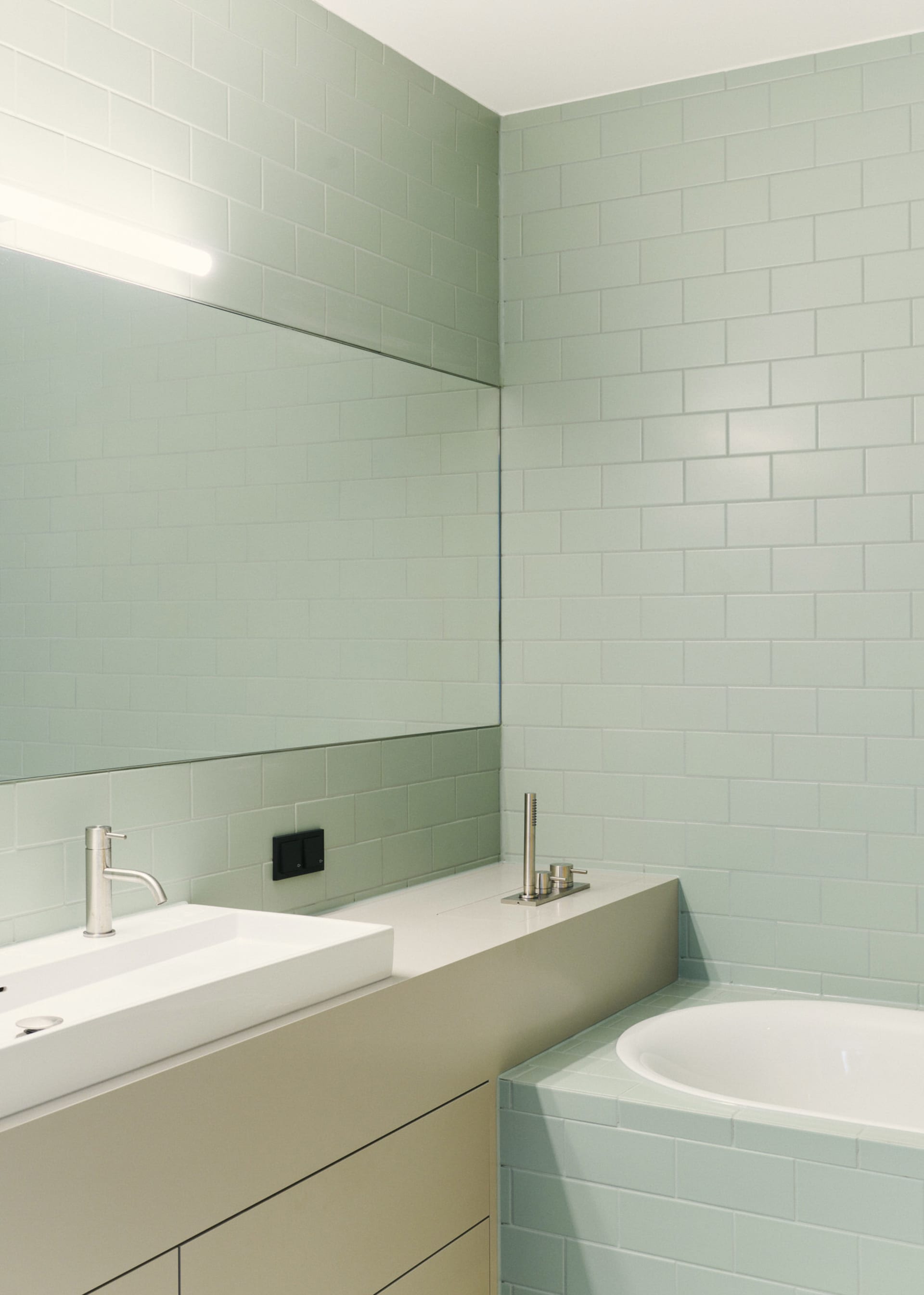 Modern minimalist bathroom featuring green glazed tiles on walls and floor.