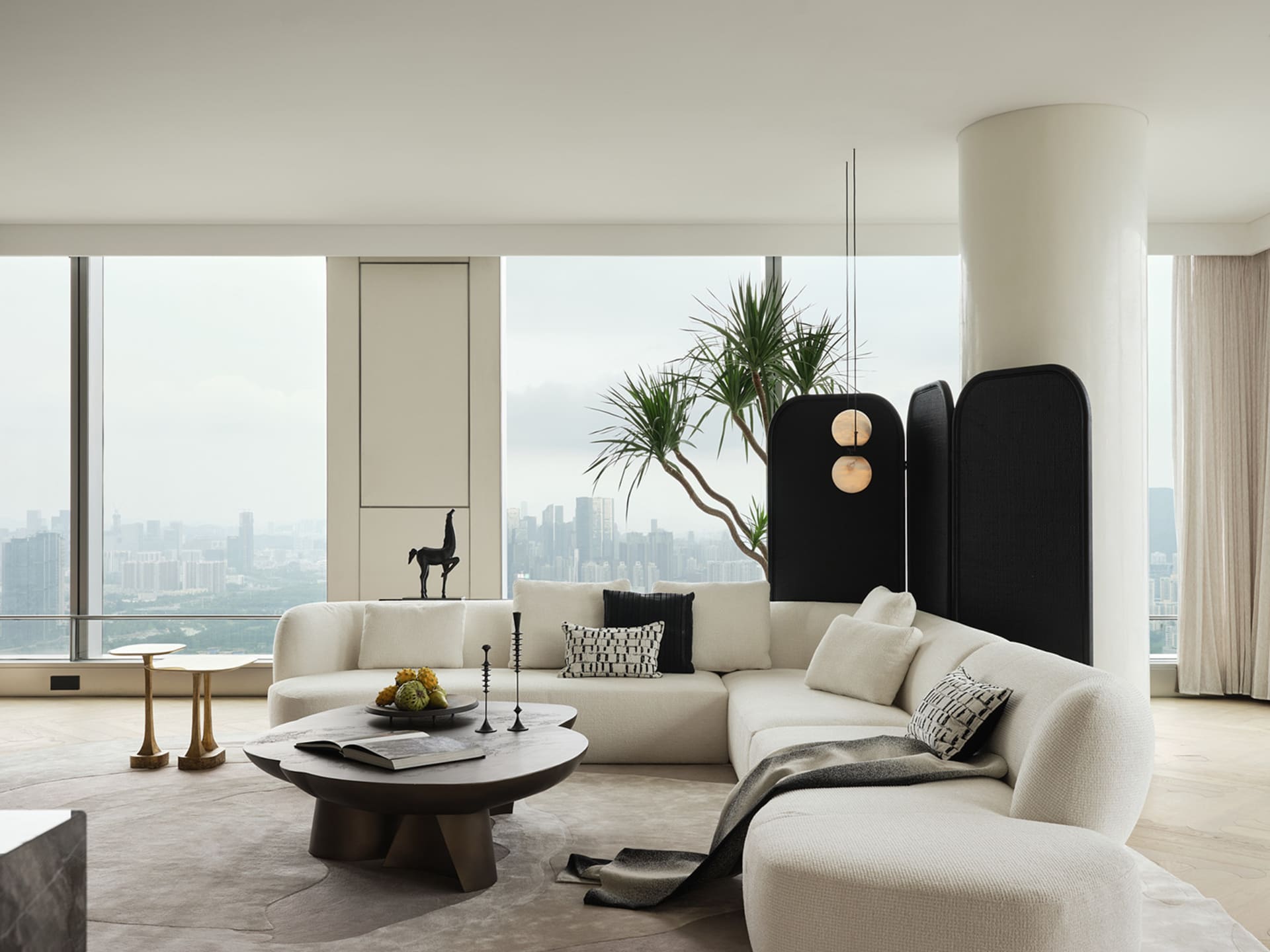 Modern white living room with black accents and a panoramic city view.