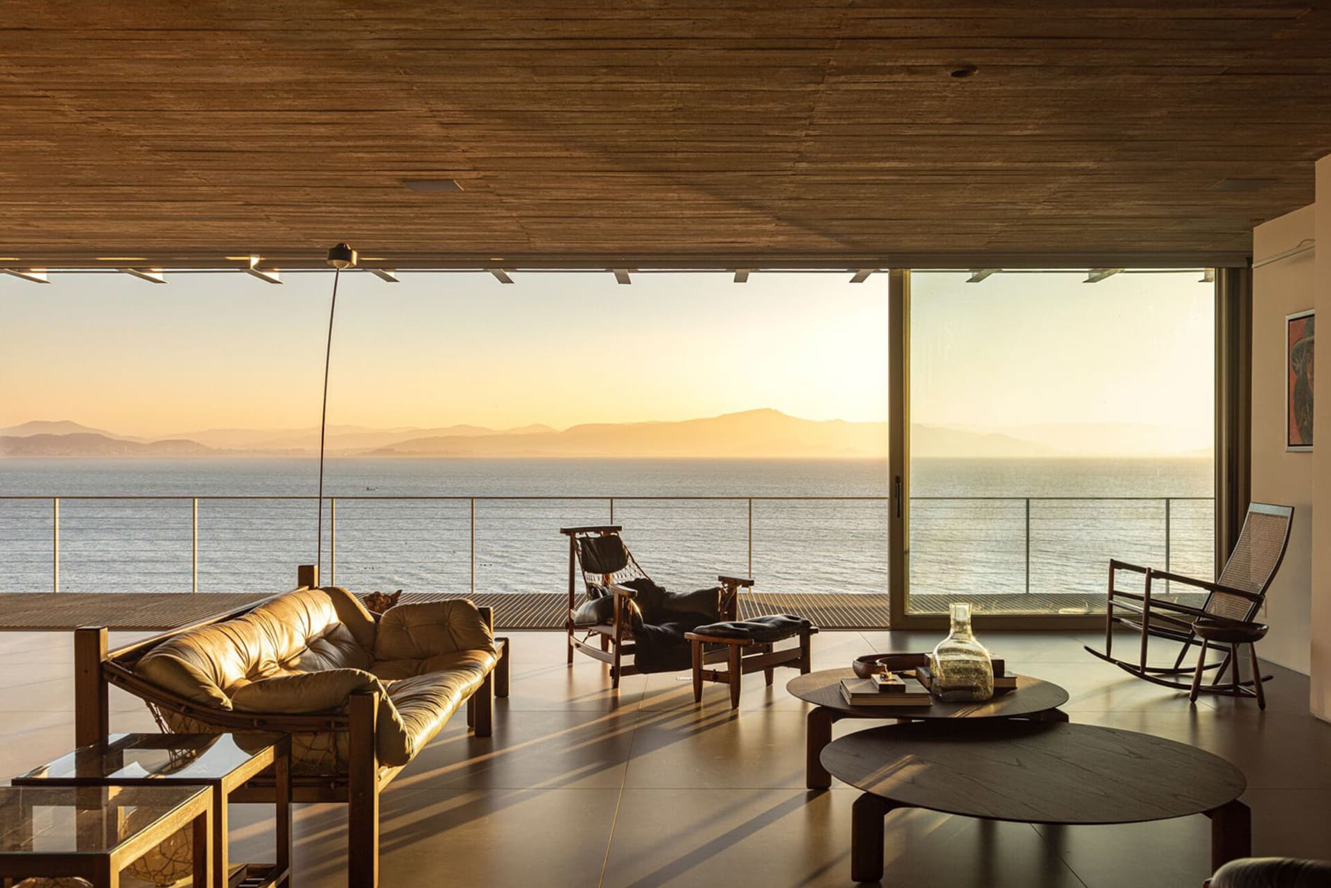 A minimalist living room featuring a glass wall with a stunning ocean view.