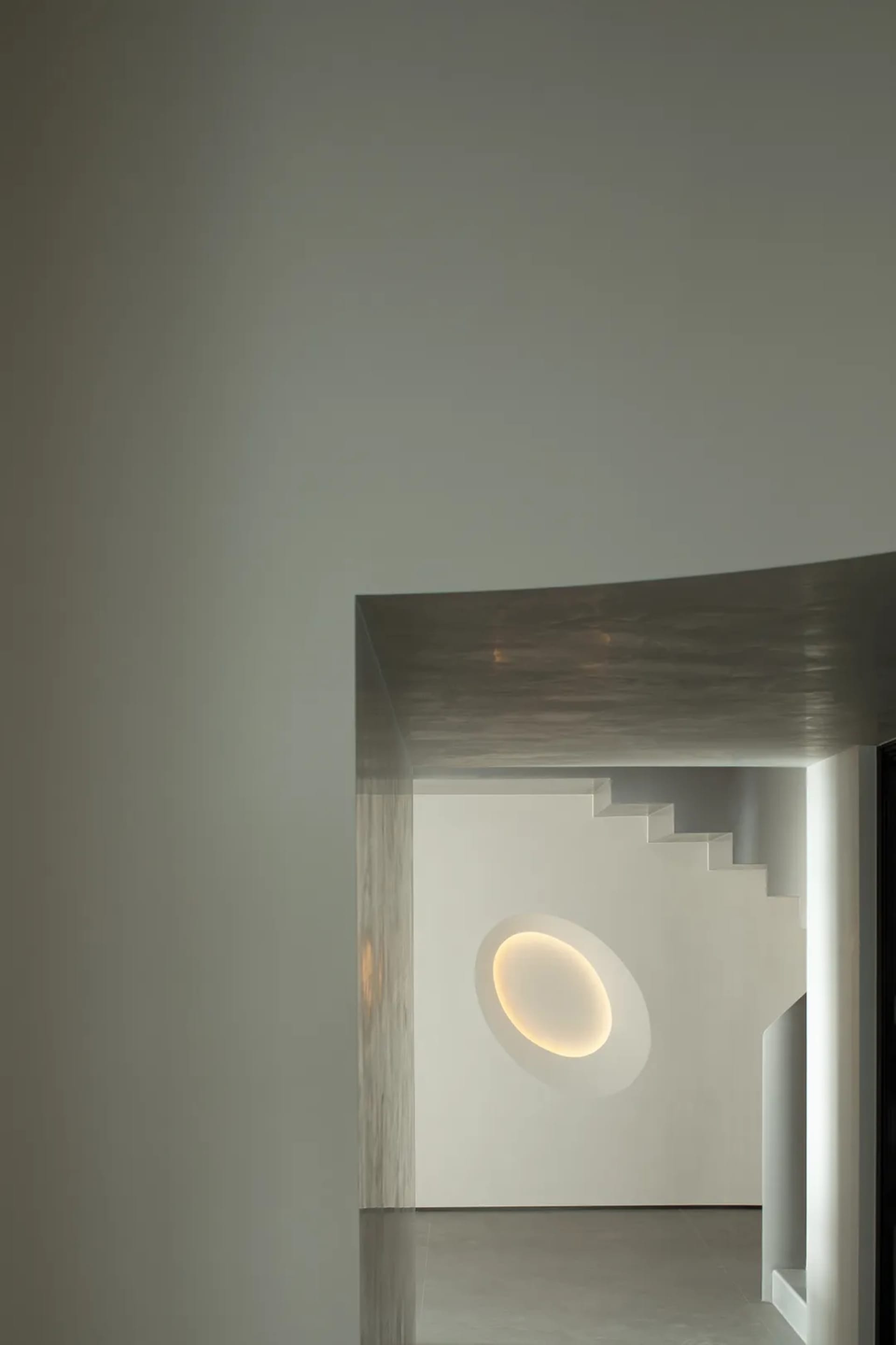 Minimalist interior design featuring a concrete staircase with warm, ambient lighting in a modern space.