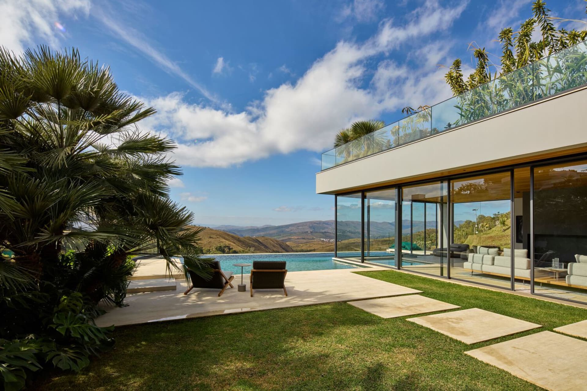 Modern pool house with glass walls, concrete patio, and steel accents.