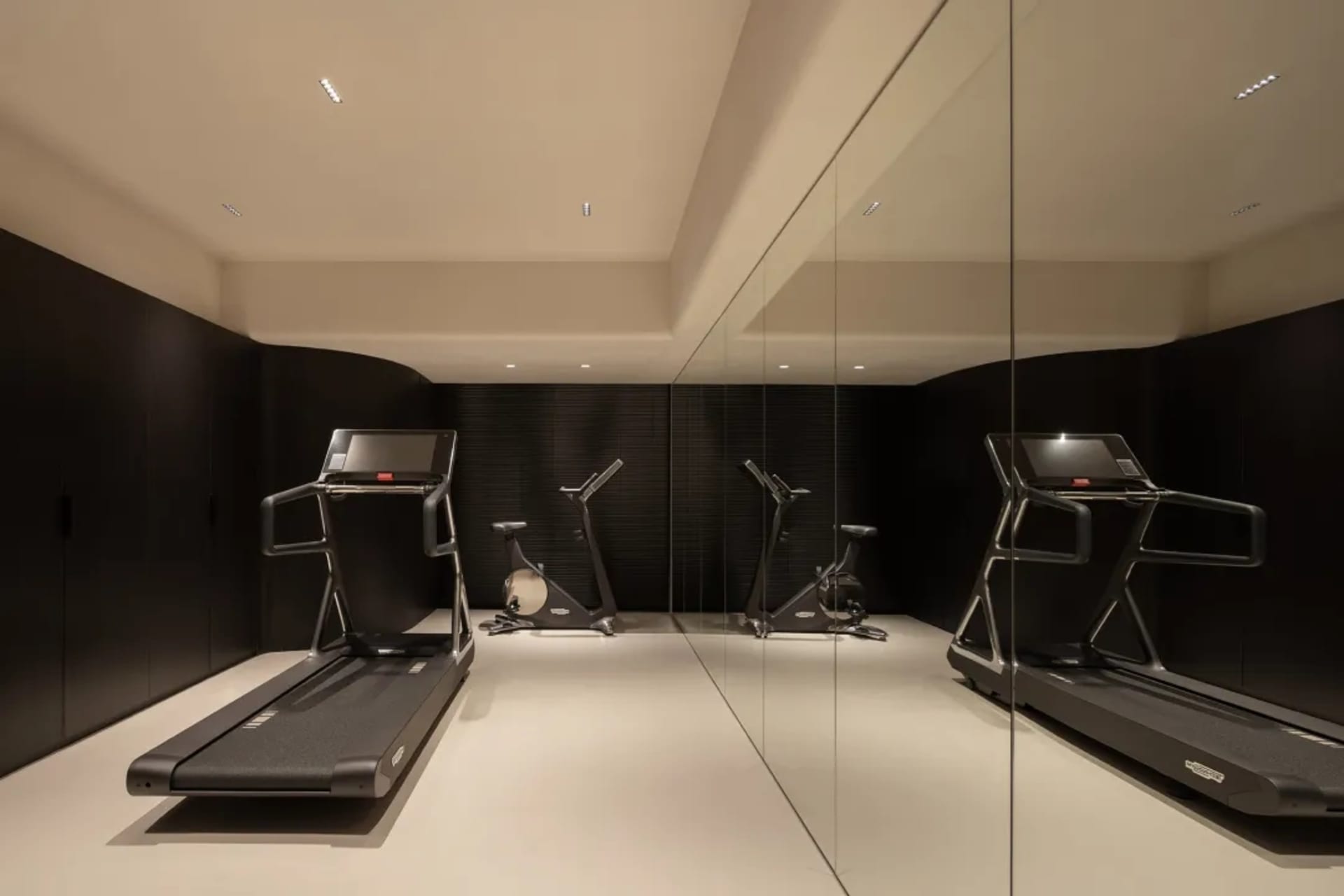 A minimalist gym room with metallic equipment and reflective surfaces.