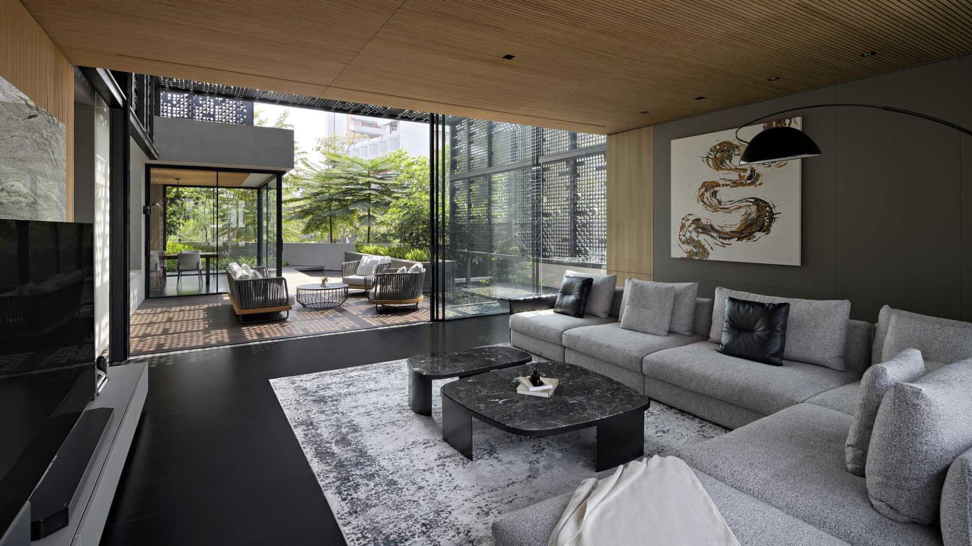 A modern minimalist living room with a large sofa, marble coffee tables, and a view of the garden through large windows.