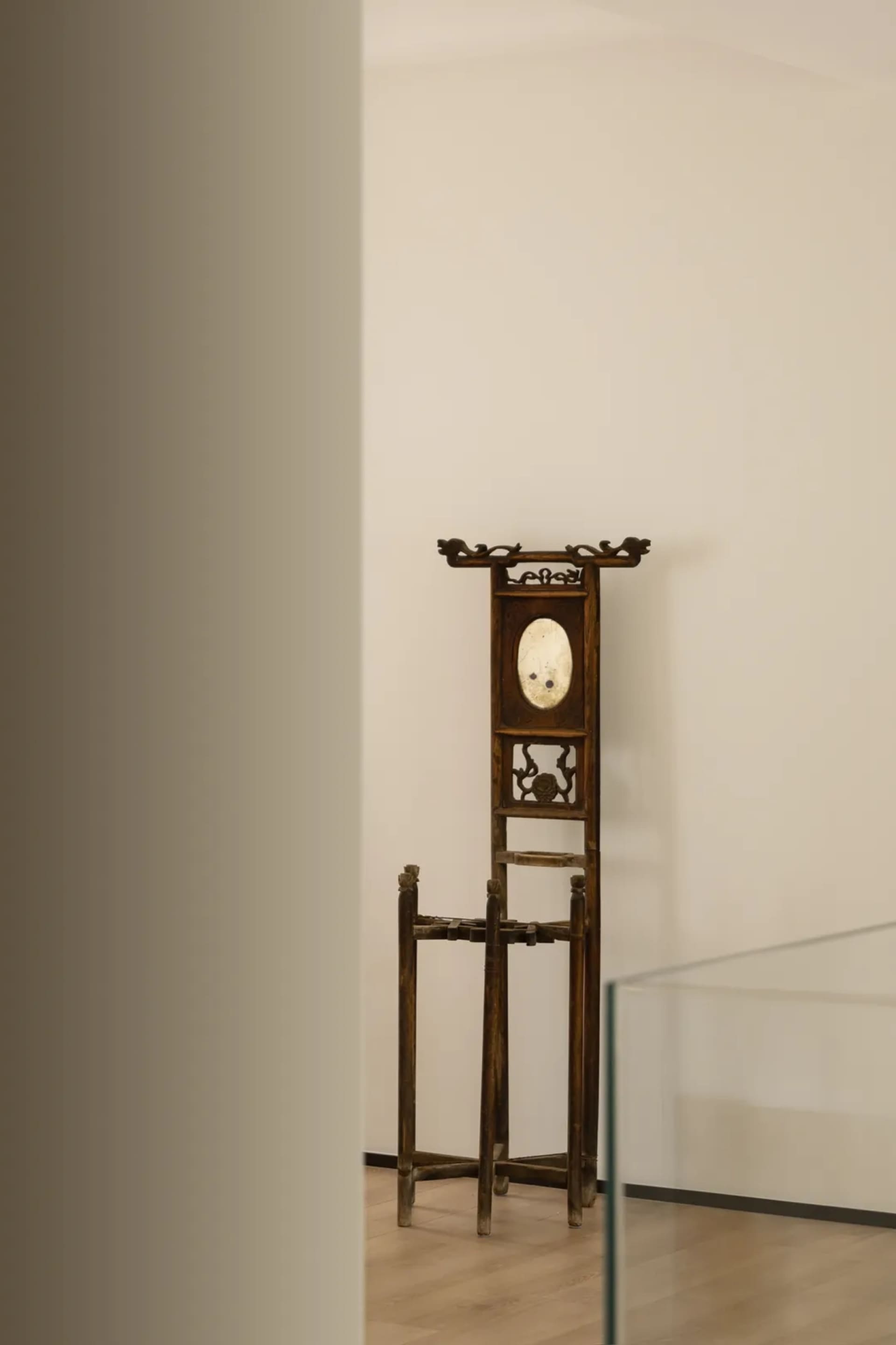 An antique wooden cloakroom rack with intricate carvings and a mirror in the center.