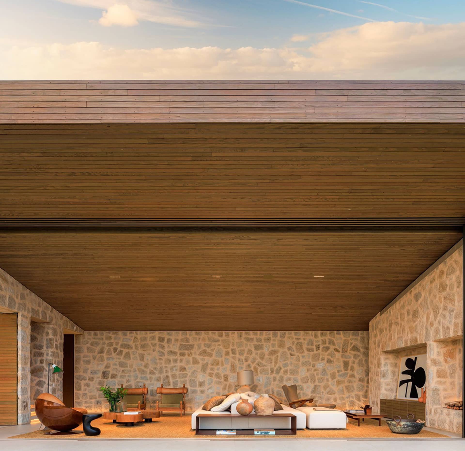 Modern living room with wooden ceiling, stone walls, and furniture.