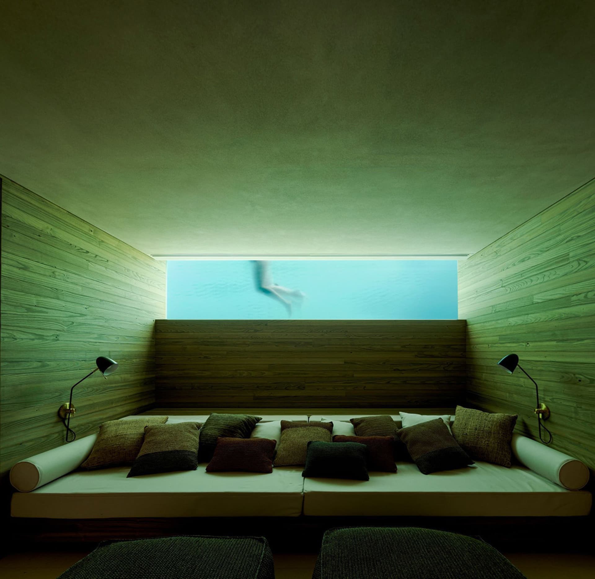 A modern living room with wooden walls and a comfortable seating area overlooking a pool.