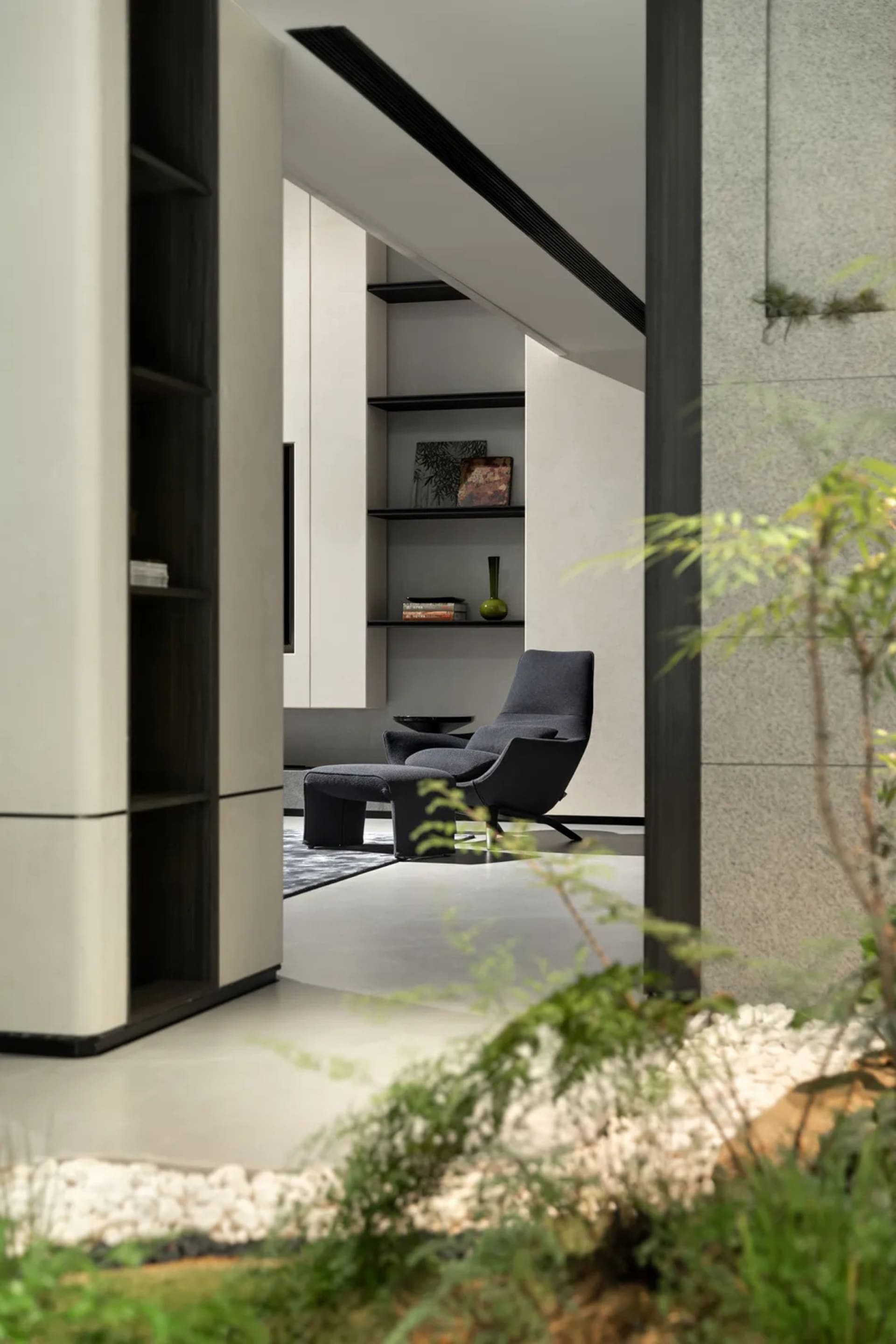 Modern living room with concrete walls and floor, featuring minimalist furniture and greenery.