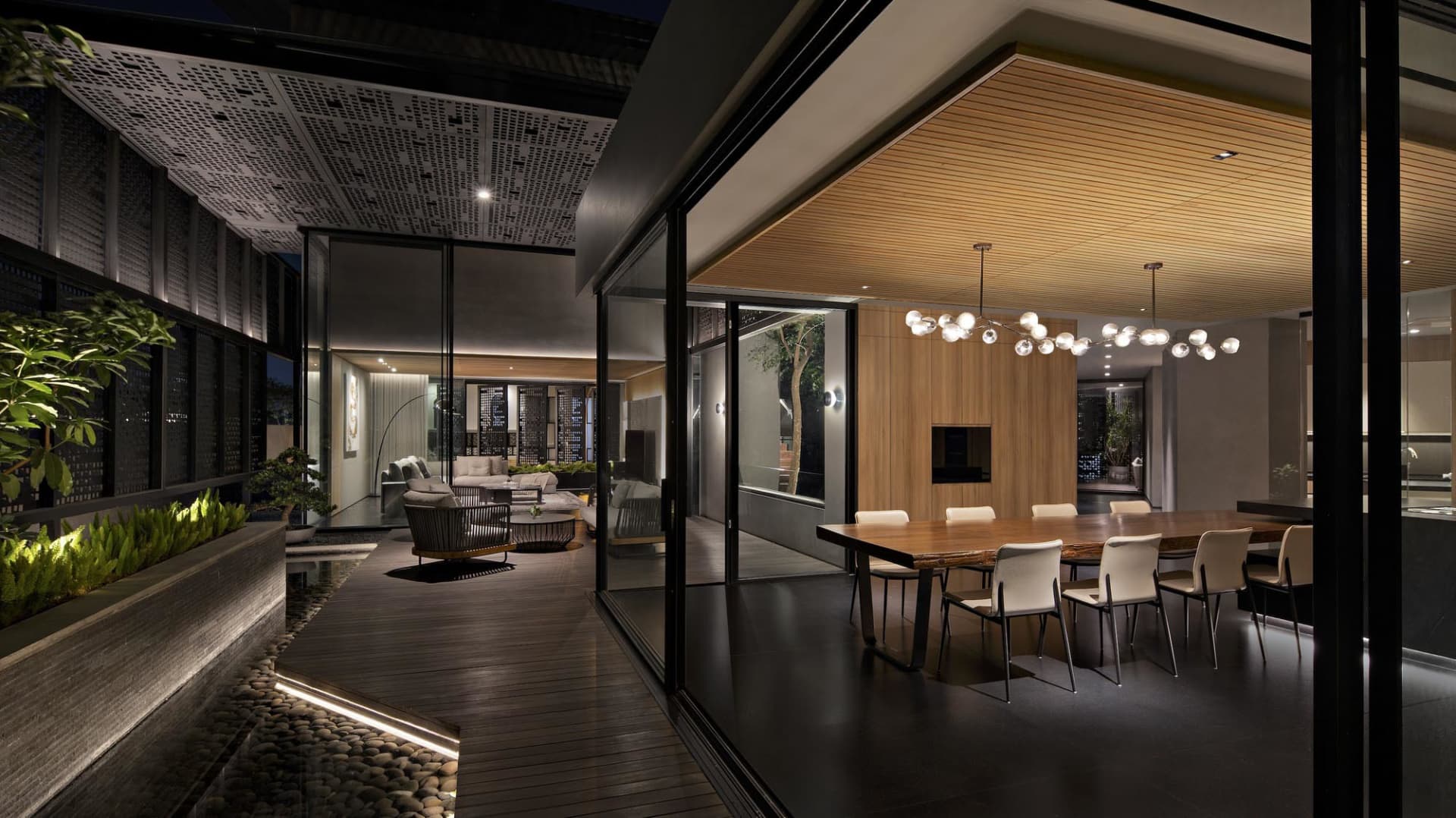 A modern living room with wooden floor and glass walls, featuring a contemporary black and white sofa and a sleek wooden coff