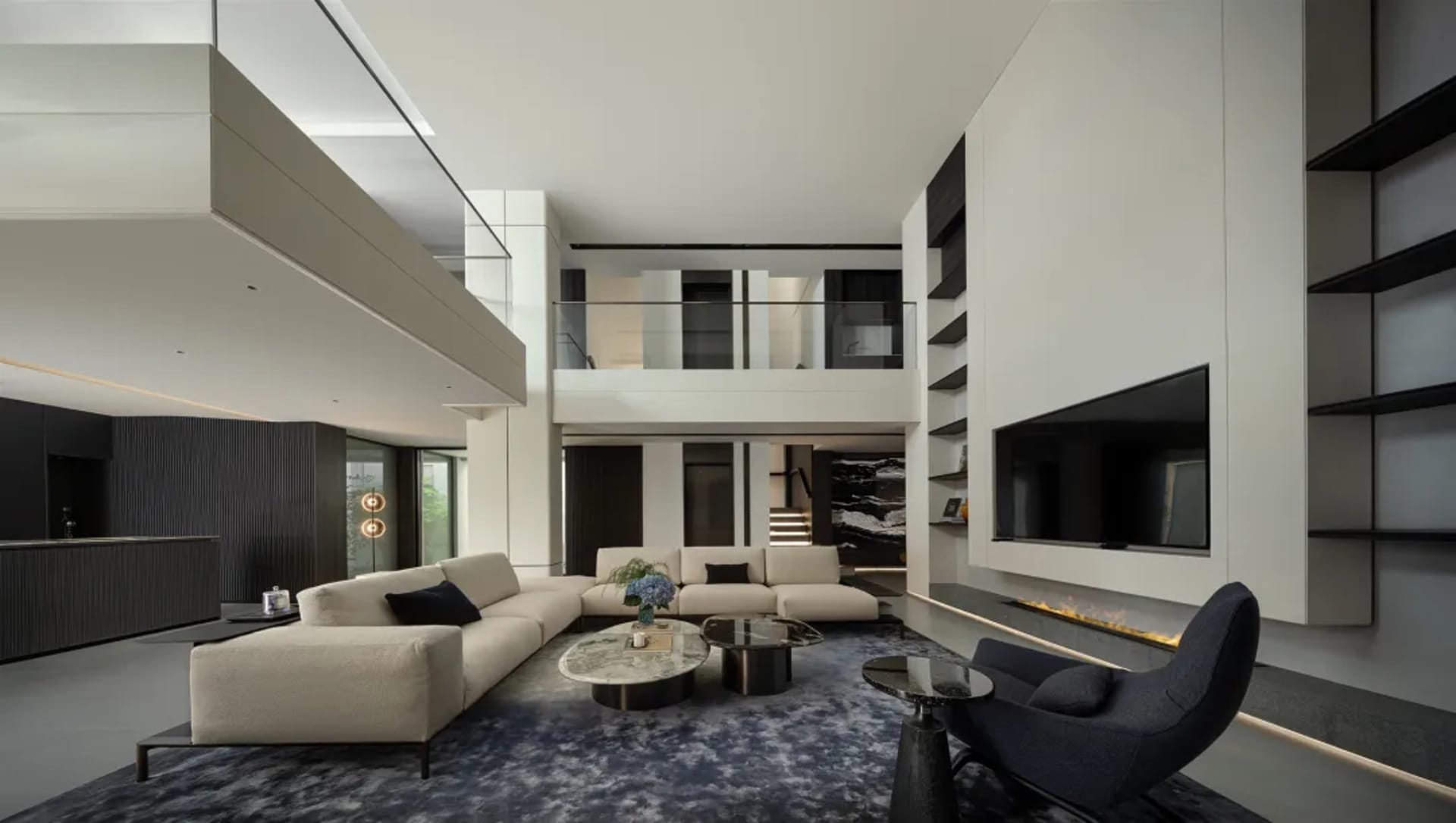 Contemporary minimalist living room with white couches, coffee tables, and a large flat-screen television in a high-ceiling m