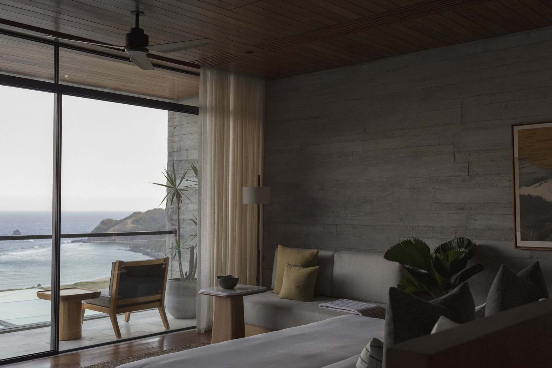 A minimalist bedroom featuring concrete, wood, and glass materials.