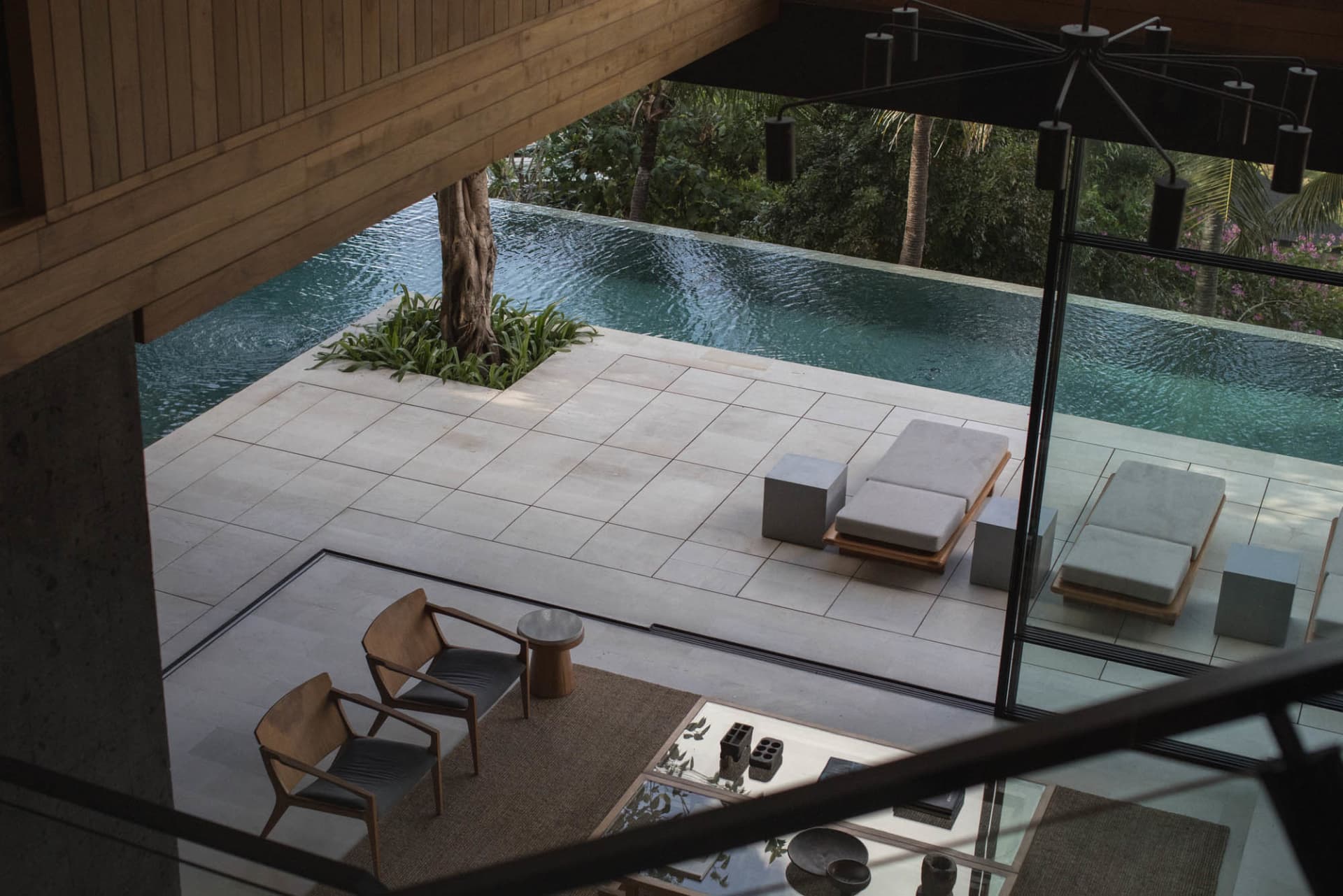 Modern, open-air residential pool deck featuring concrete blocks and tiled flooring.