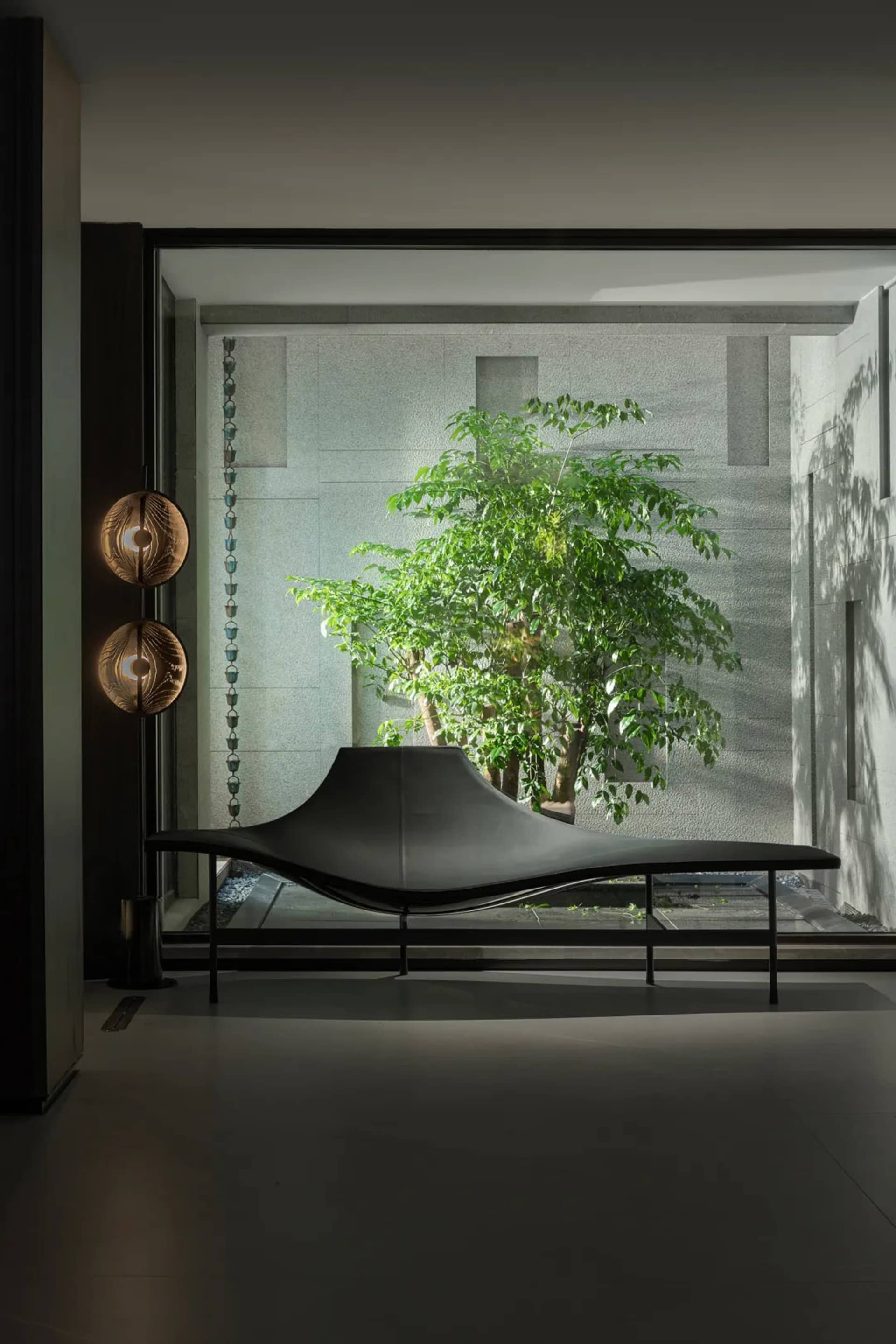 A sleek, minimalist leather sofa with an abstract, flowing shape, positioned against a backdrop of concrete walls in a contem